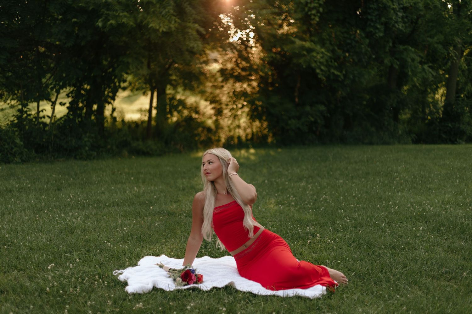 Portrait session in grassy field with person in red dress at sunset.