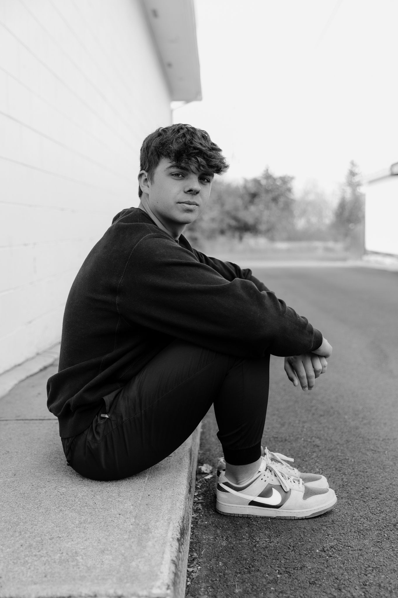 Black and white artistic photo series showing someone sitting on ground wearing Nike sneakers in three similar poses.