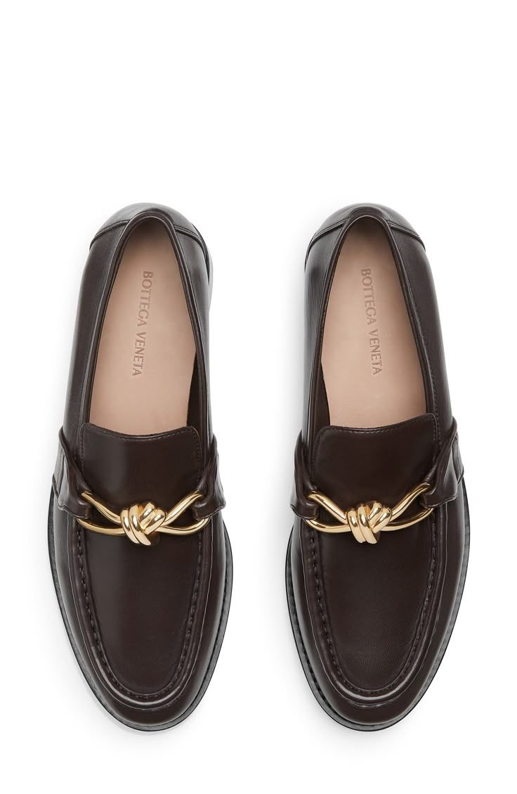 Three pairs of brown leather baby moccasins with gold bow accents shown from different angles.