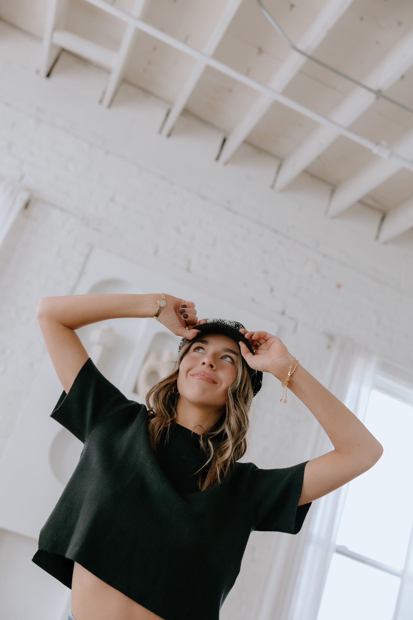 Artful fashion photoshoot in white room featuring dramatic poses and black t-shirt against architectural detail.