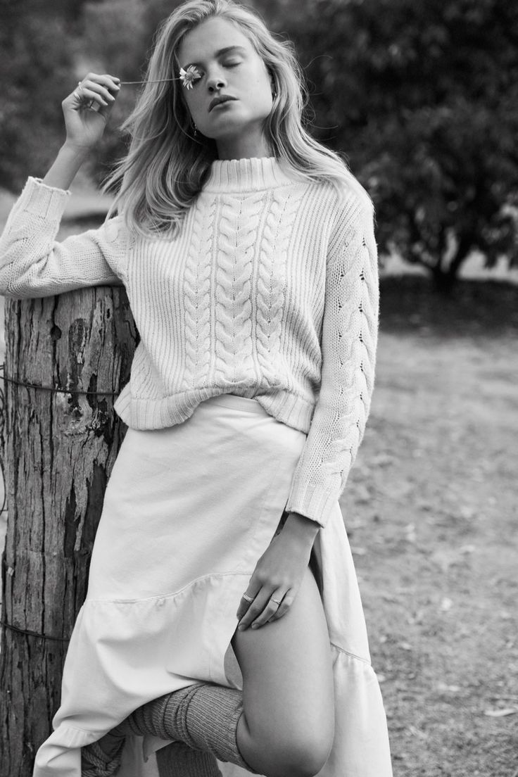 Black and white fashion photo showing a cozy cable knit sweater paired with a light flowy skirt and knee socks.