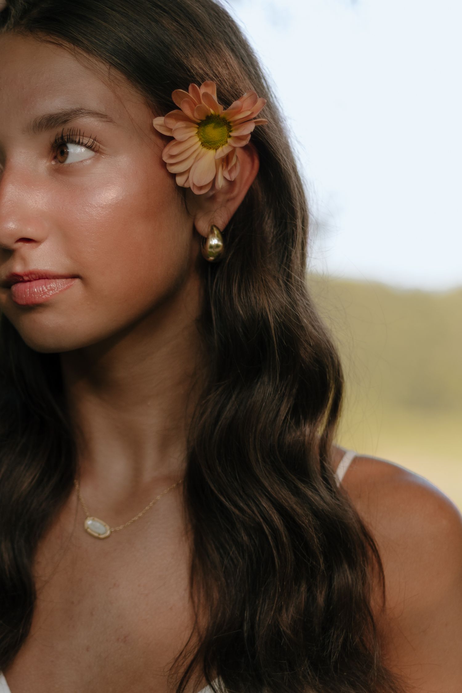 Profile portrait series with orange flower accessory and natural styling.