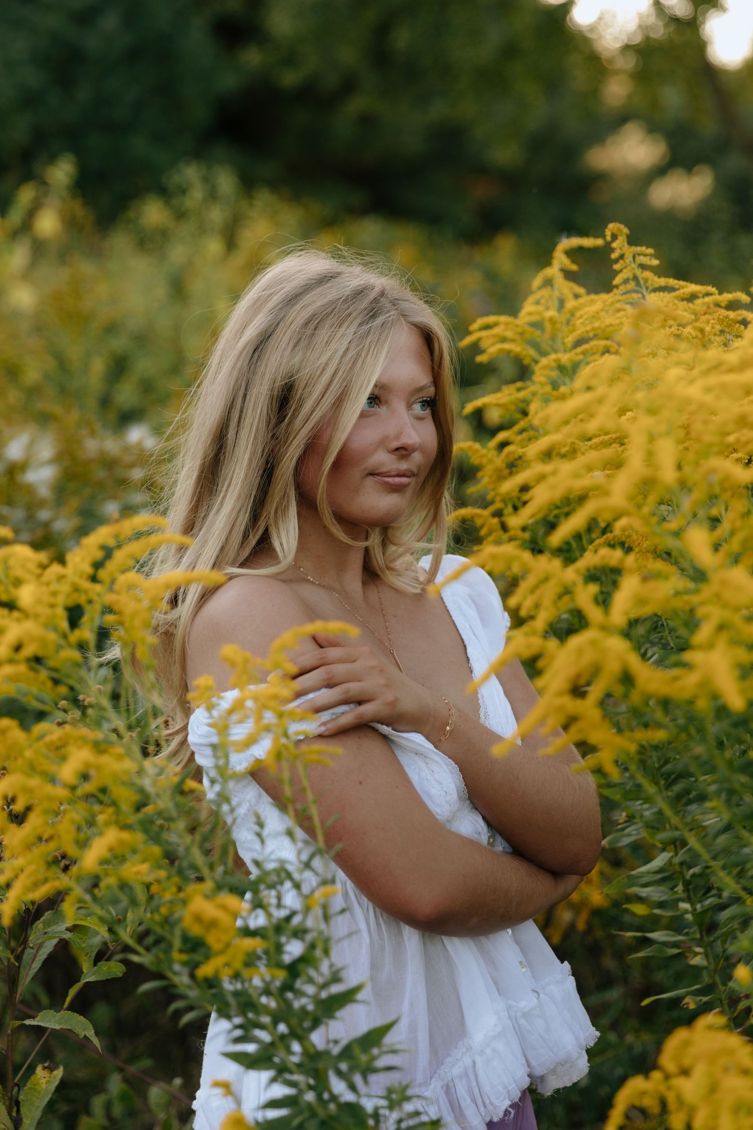 A white sundress stands out against vibrant yellow goldenrod flowers in a summer garden setting.