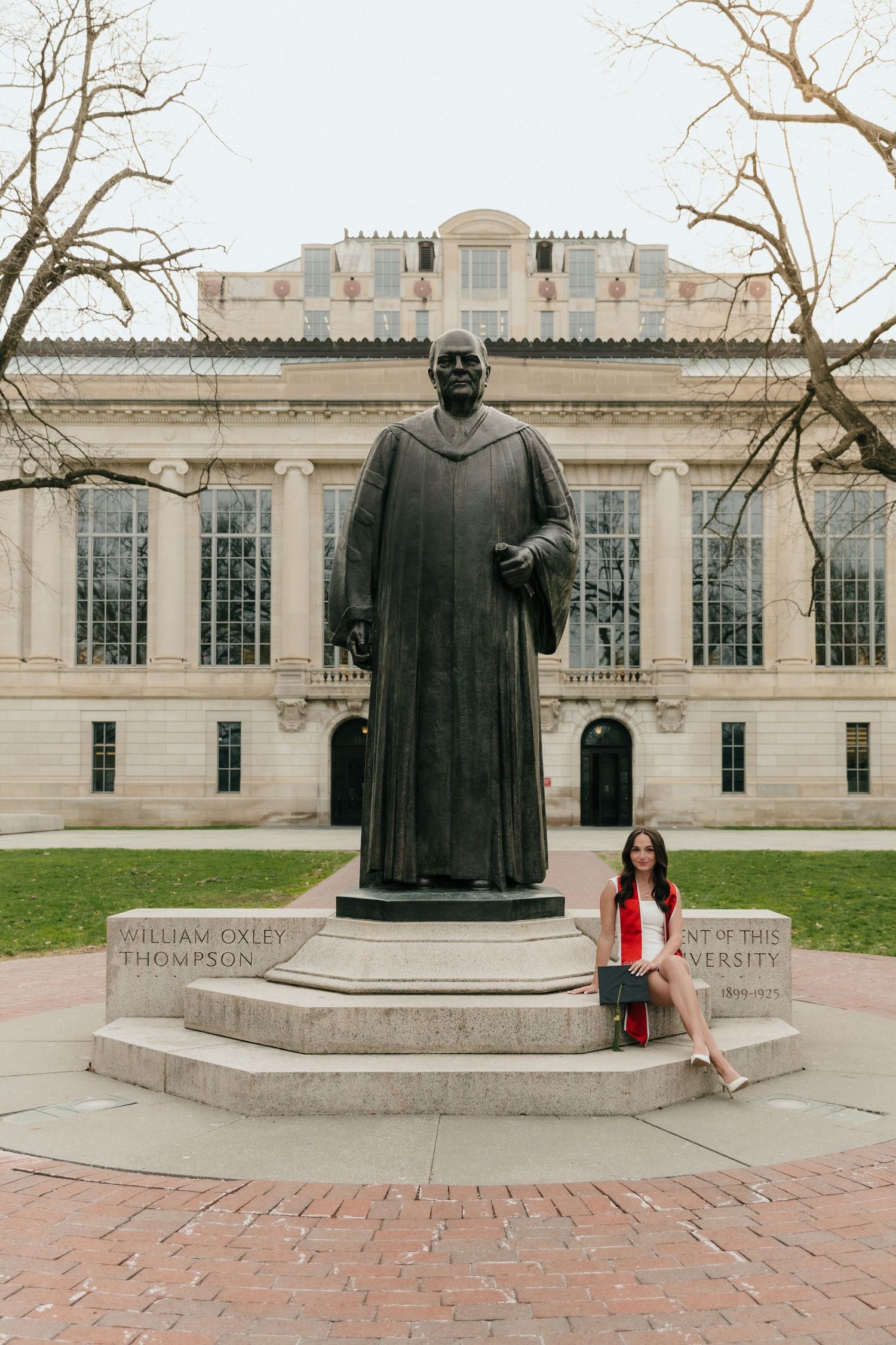 Graduate posing beside William Oxley Thompson statue at Ohio State University campus.