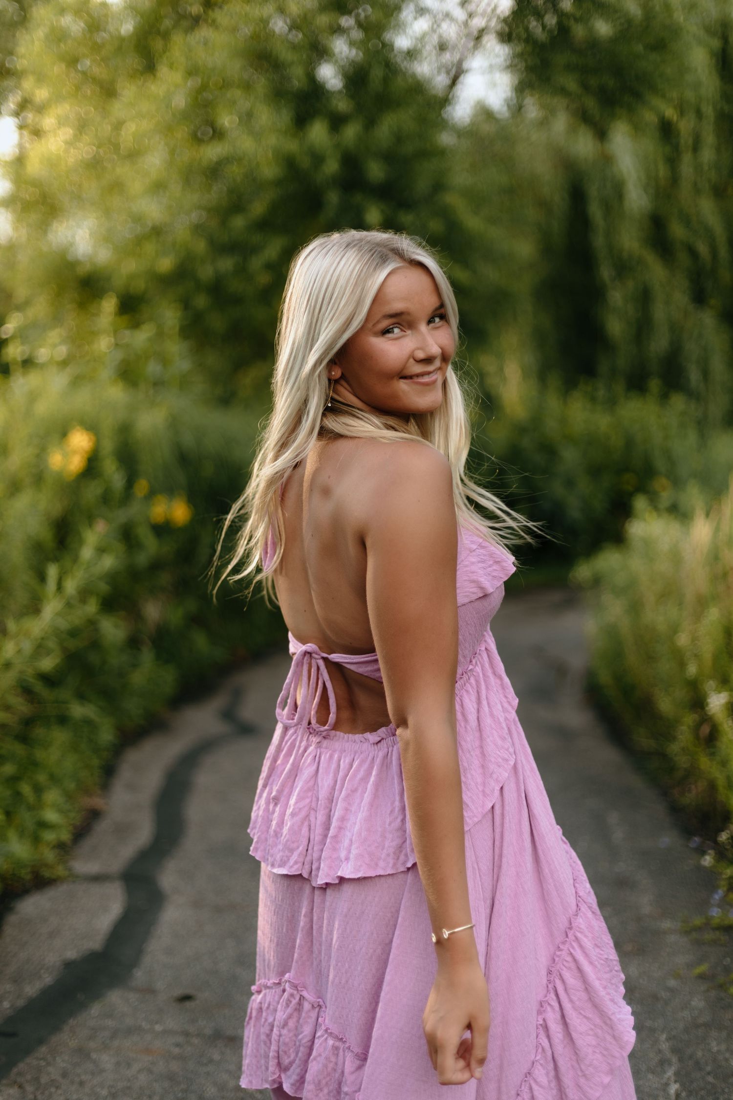 Summer garden portrait in pink ruched dress on winding path.