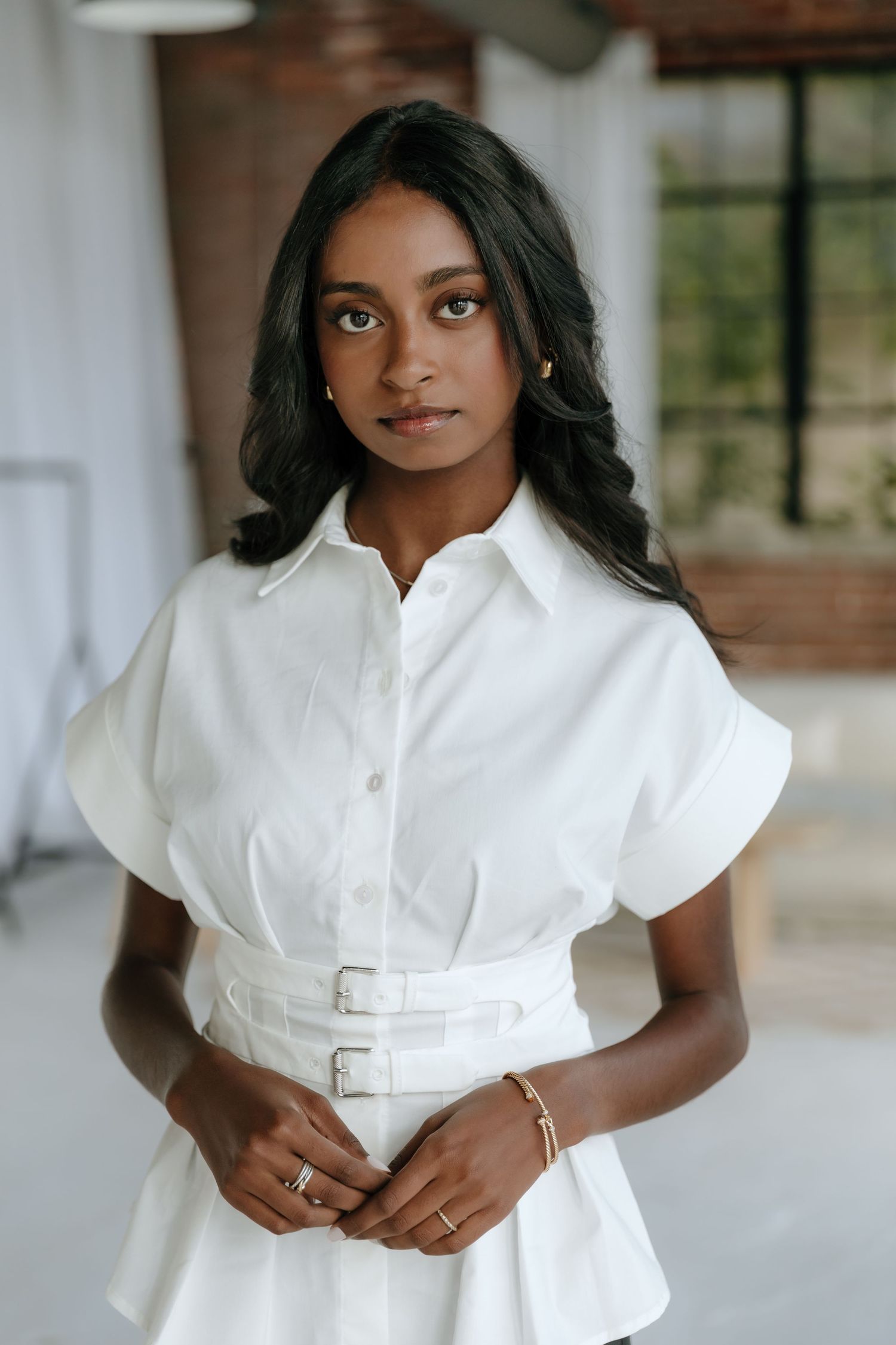 Fashion portrait series showcasing a crisp white belted top in an elegant indoor setting.