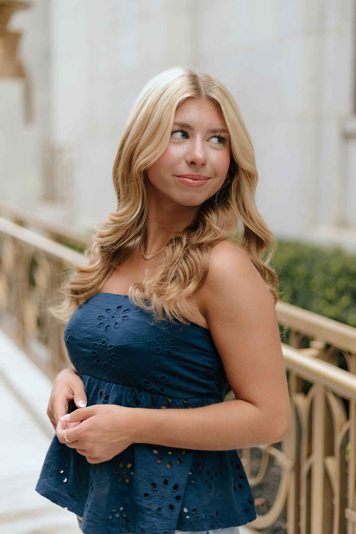 A person in a navy blue strapless dress poses against a light-colored background in a series of casual portraits.