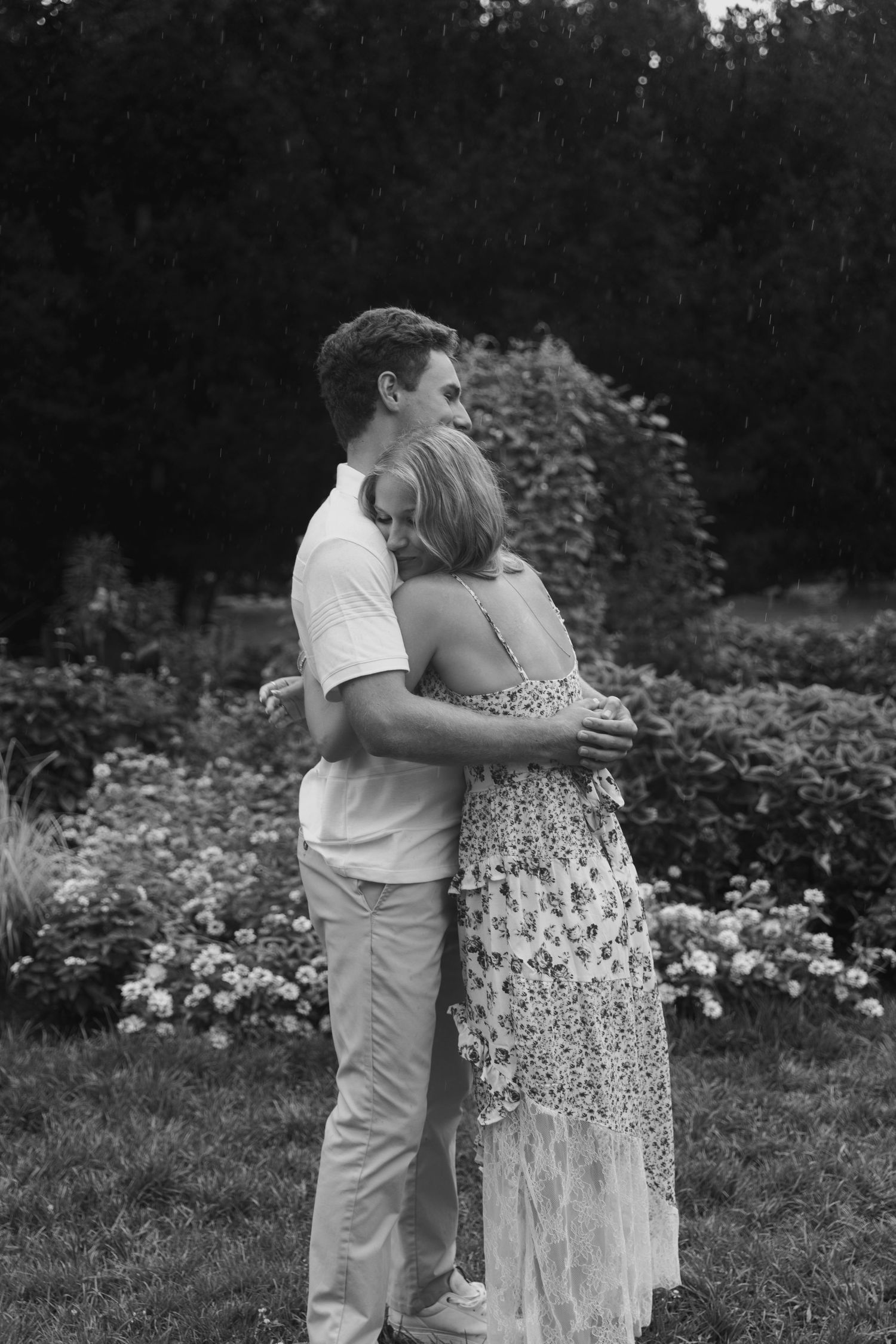 Intimate black and white portrait of couple embracing in garden setting.