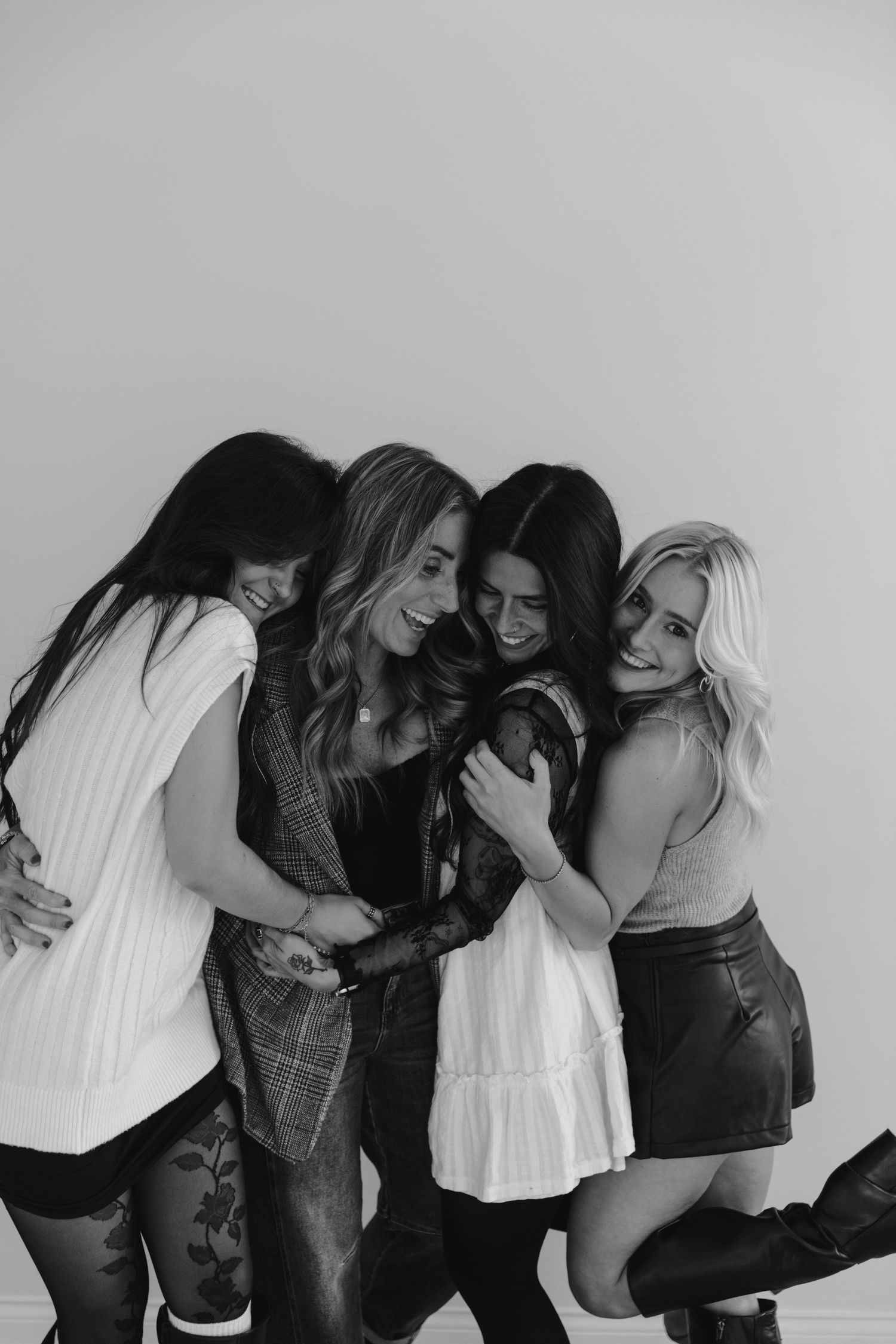 Black and white photo series showing a group of friends laughing and embracing in casual poses.