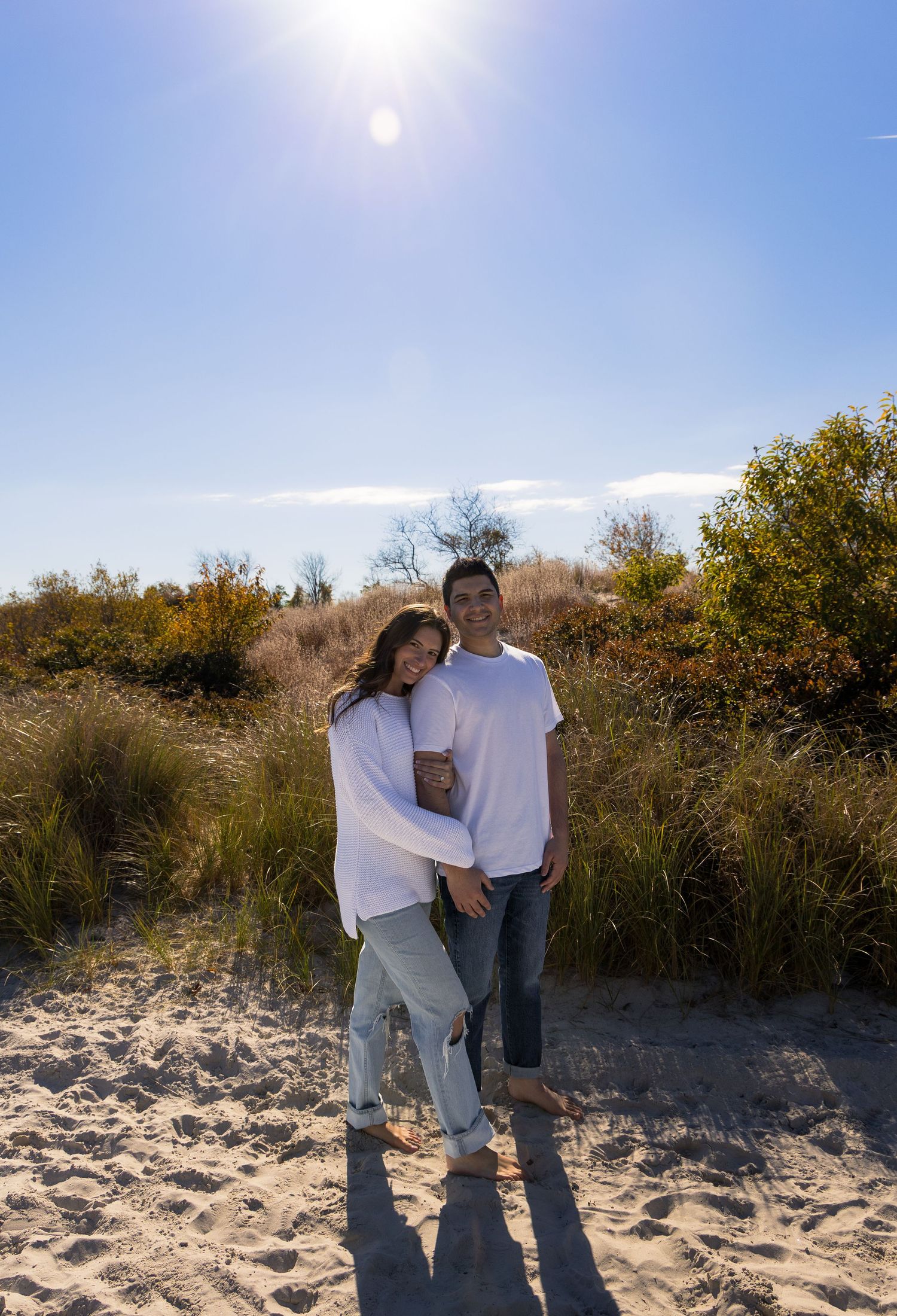 Warm beach engagement photoshoot with couple holding hands, includes a gorgeous landscape and sky