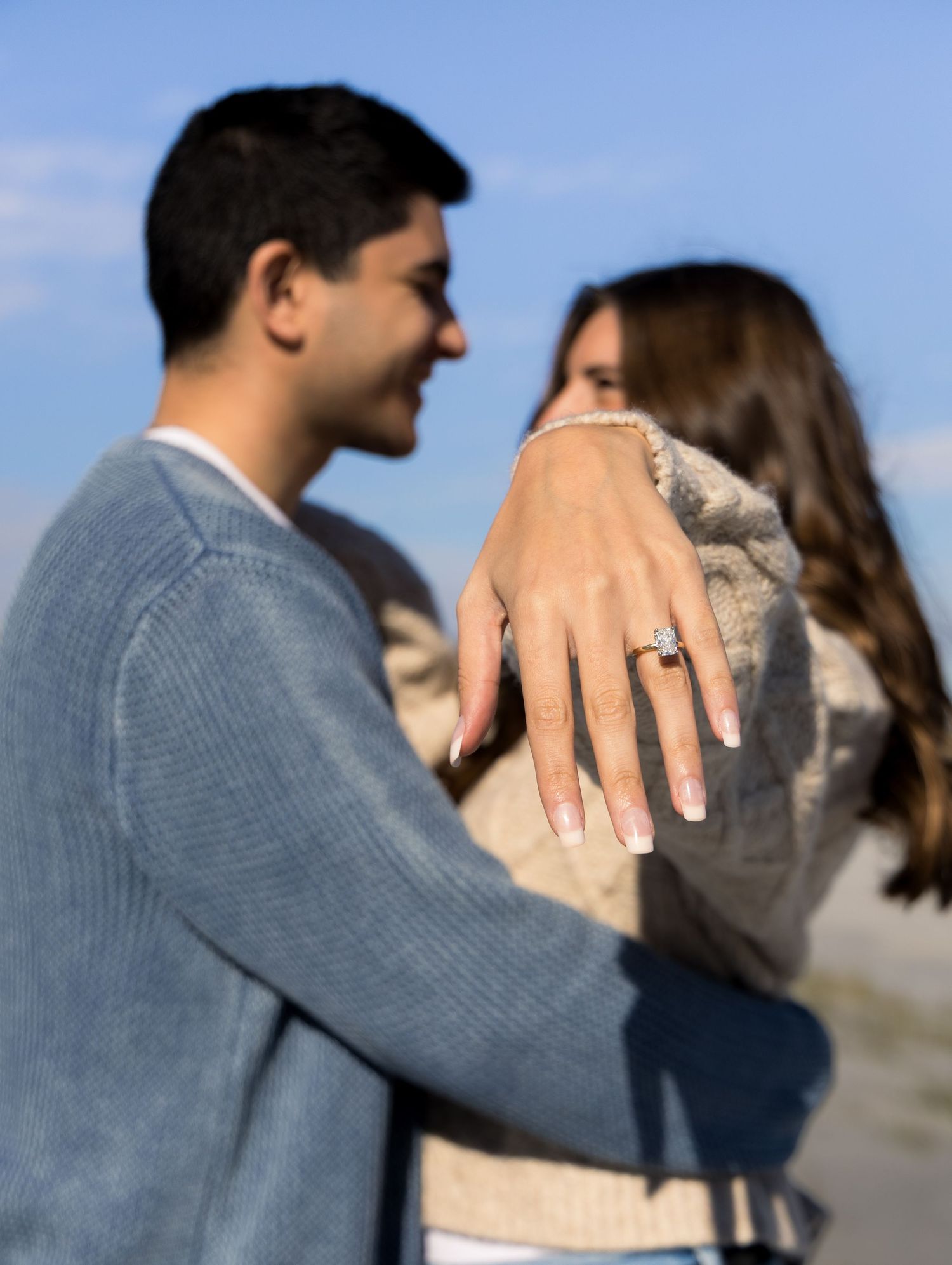 Engagement photoshoot with couple looking at each other with the engagement ring front and center