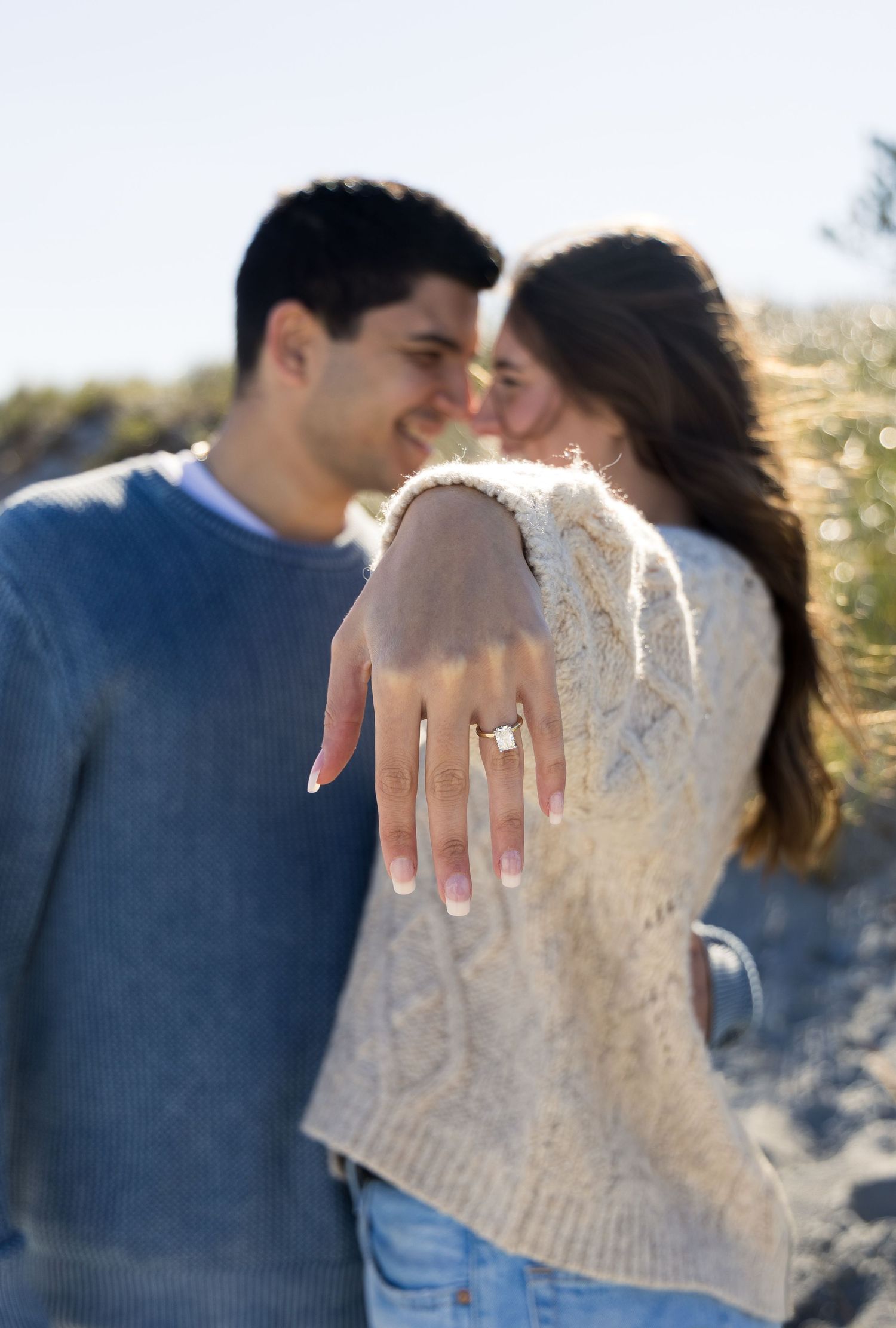 Engagement photoshoot with couple touching forehead to forehead with the engagement ring front and center