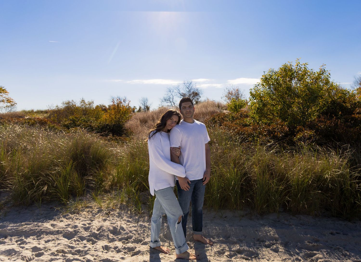 Warm beach engagement photoshoot with couple holding hands, includes a gorgeous landscape and sky