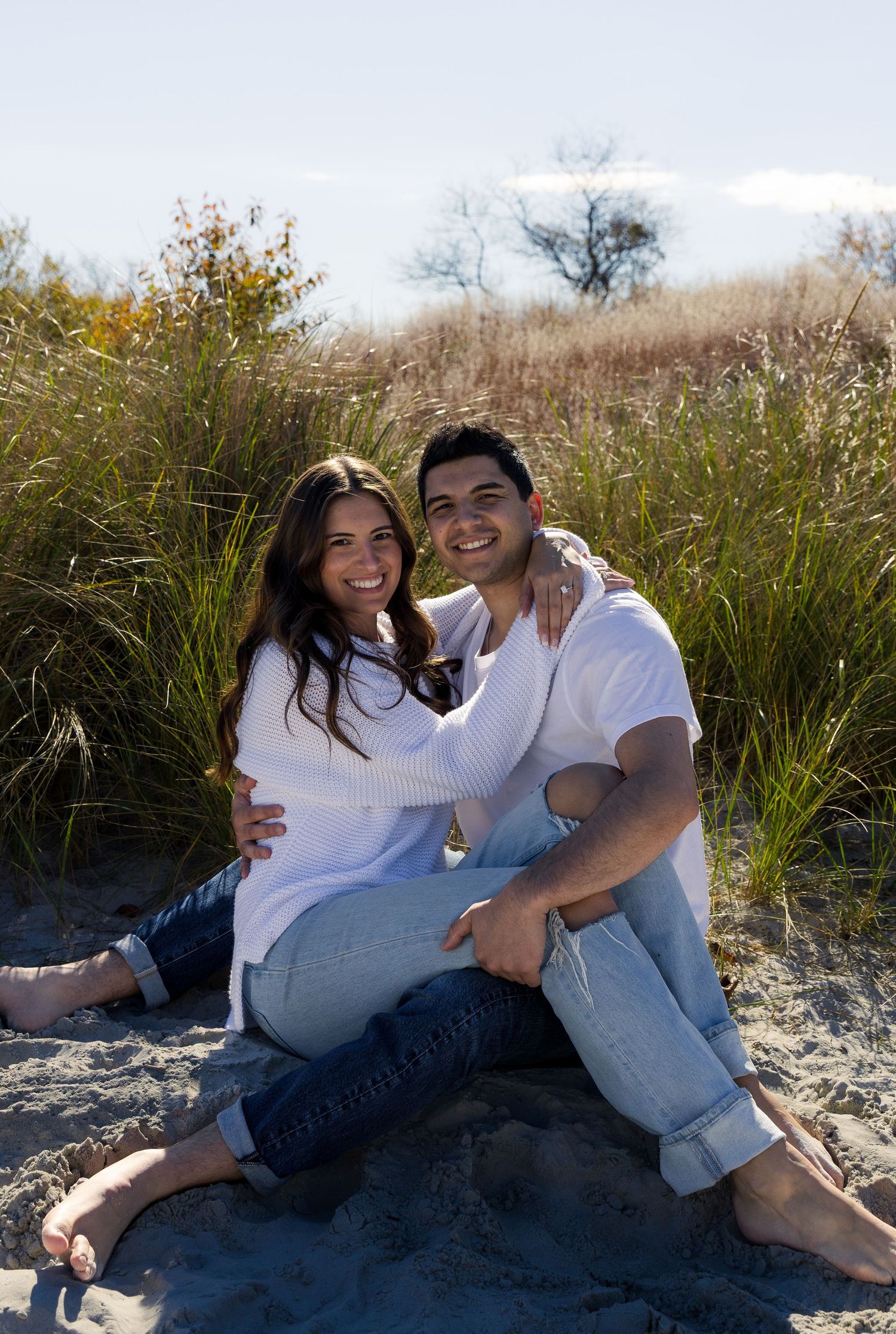 Outdoor engagement photoshoot featuring smiling couple wrapped in each others arms
