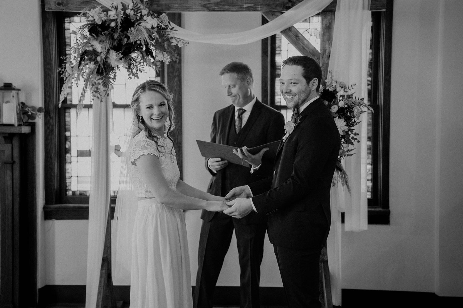 Black and white photo of couple exchanging vows at rustic altar.