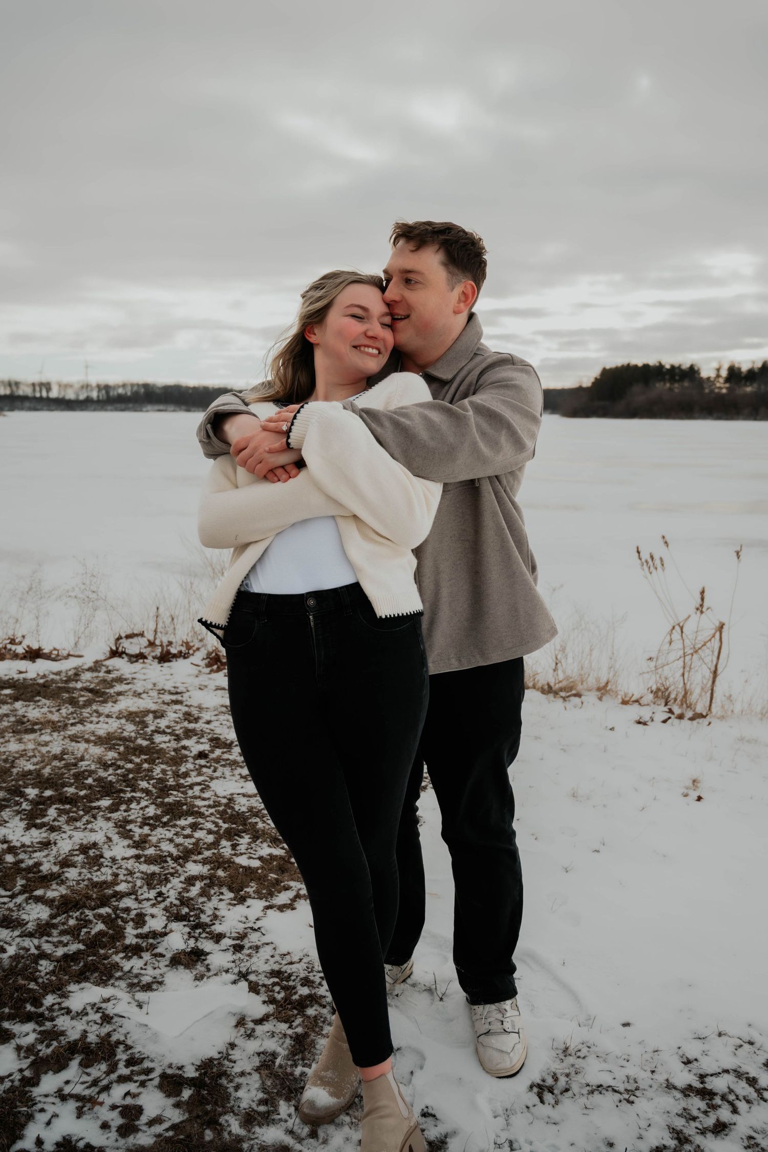Happy couple embracing in a snowy winter landscape outdoors.