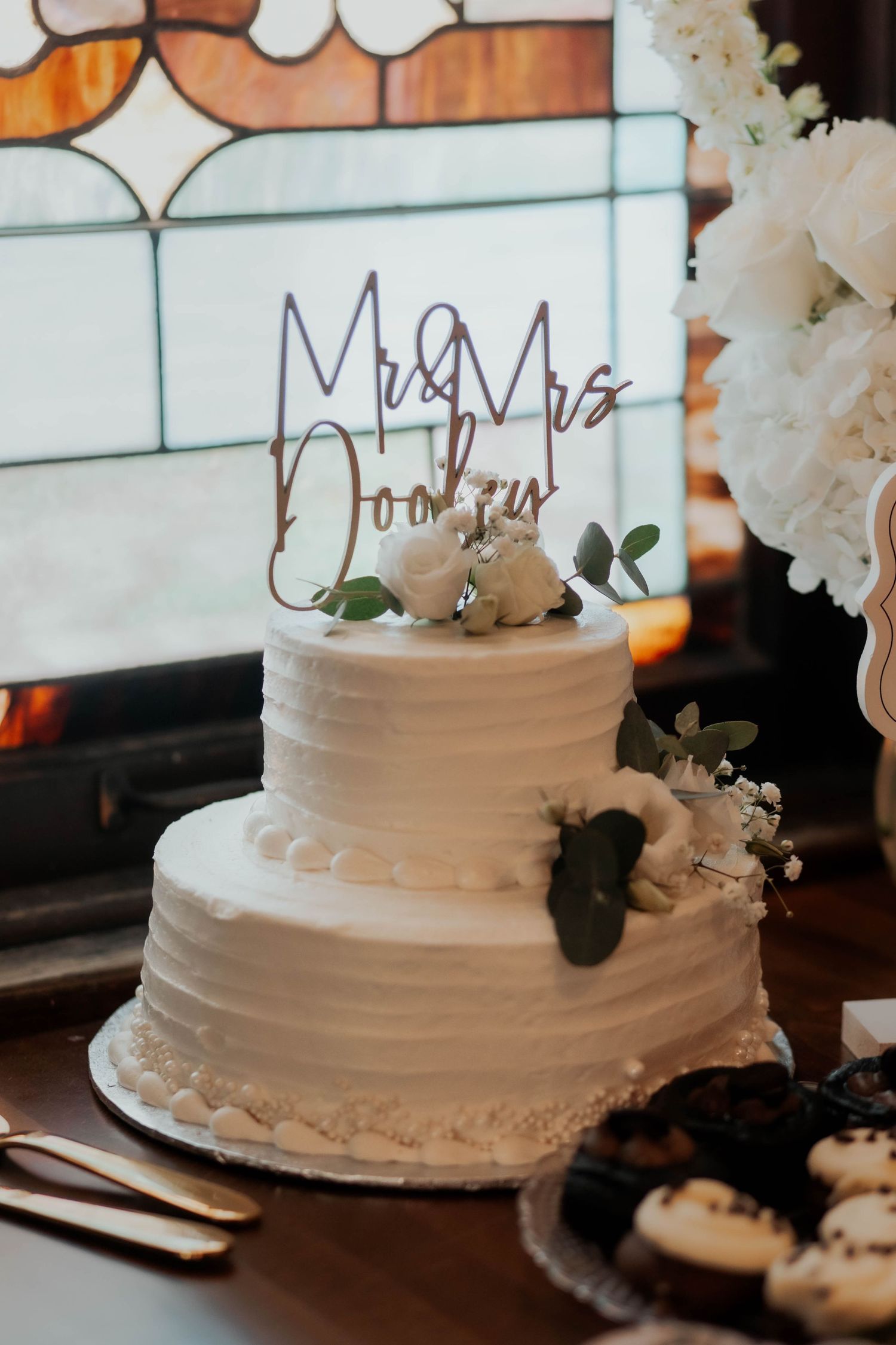 Elegant two-tier white wedding cake with Mr and Mrs Dooley topper.