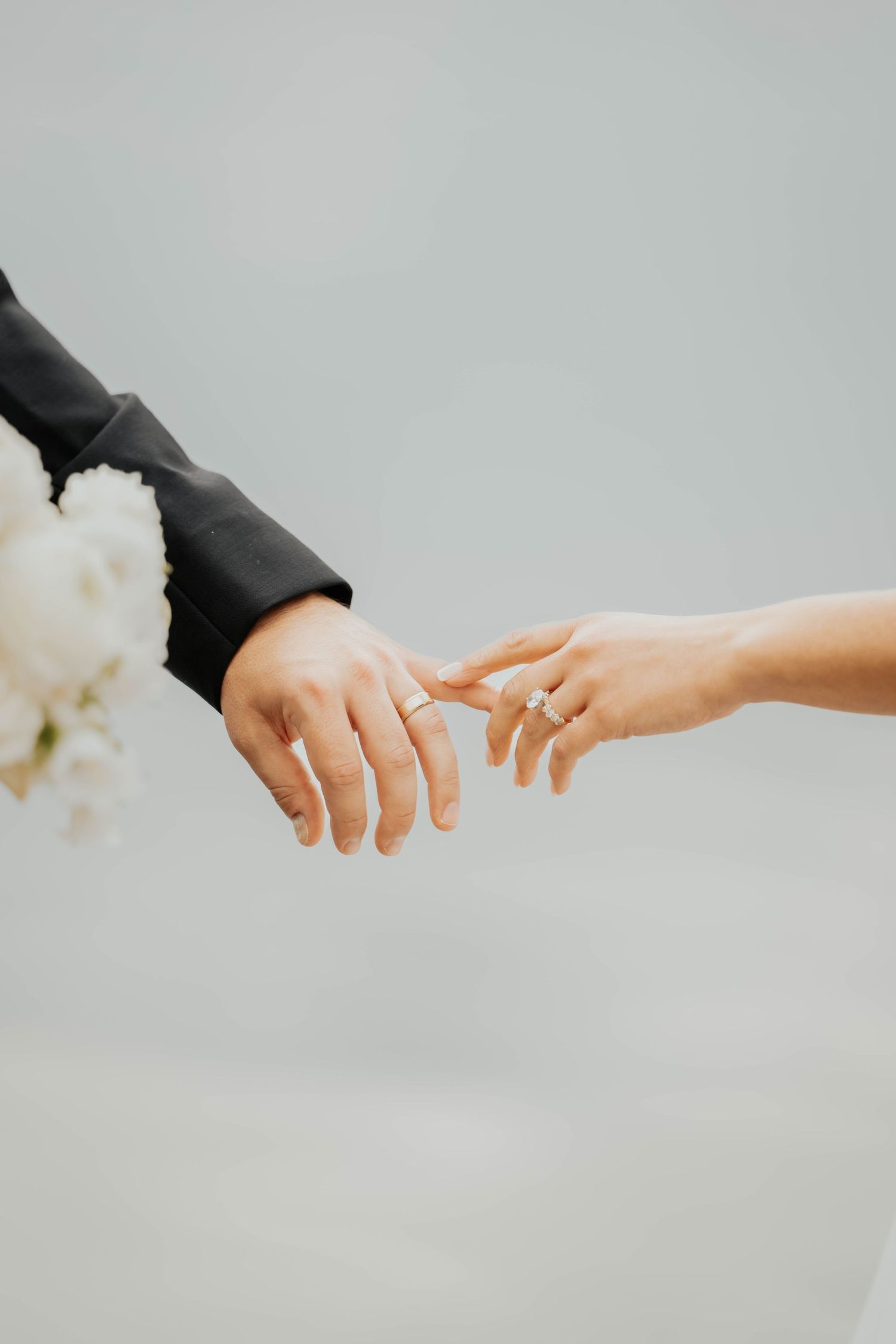 Close-up of bride and groom touching hands showing wedding bands and diamond engagement ring.