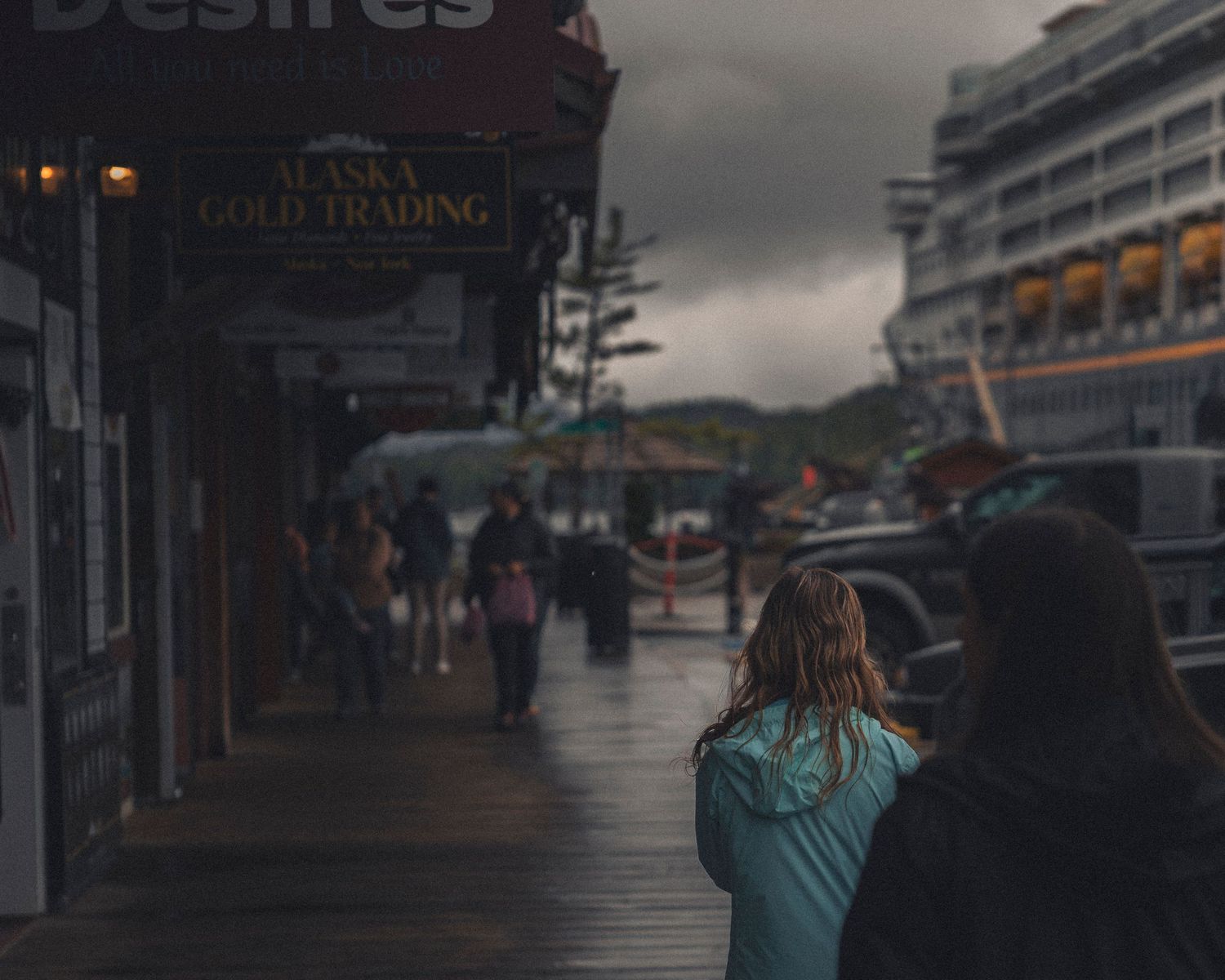 Dark silhouettes of tourists walking along a cruise ship deck at dusk.