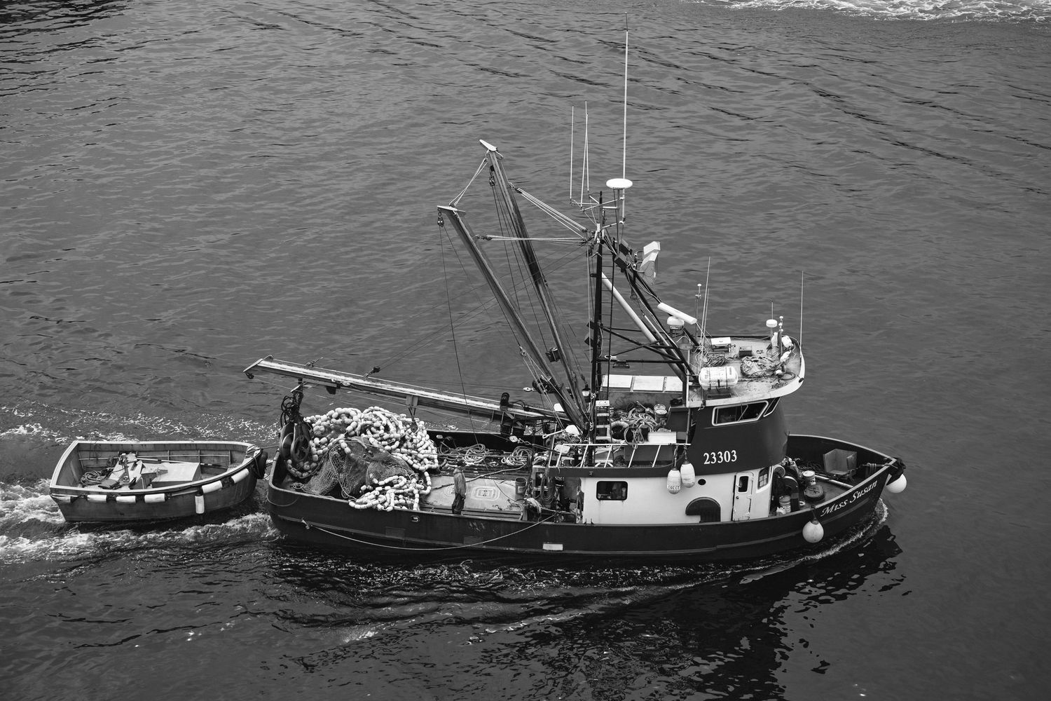 Commercial fishing boats lined up in dark waters with fishing equipment visible on their decks.