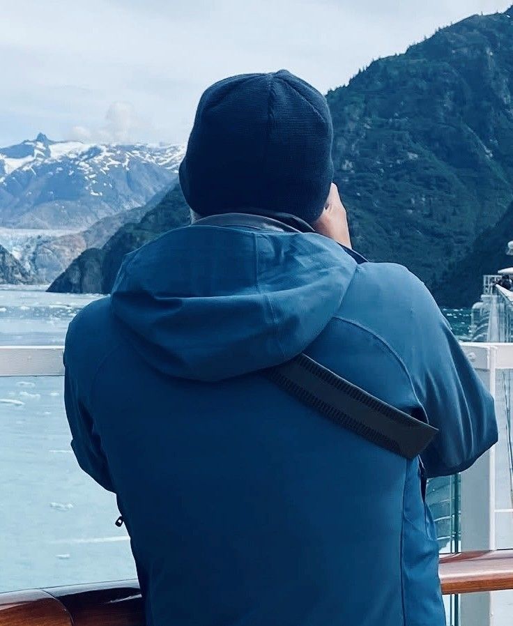 View of snow-capped mountains and glaciers from a cruise ship deck on an overcast day.
