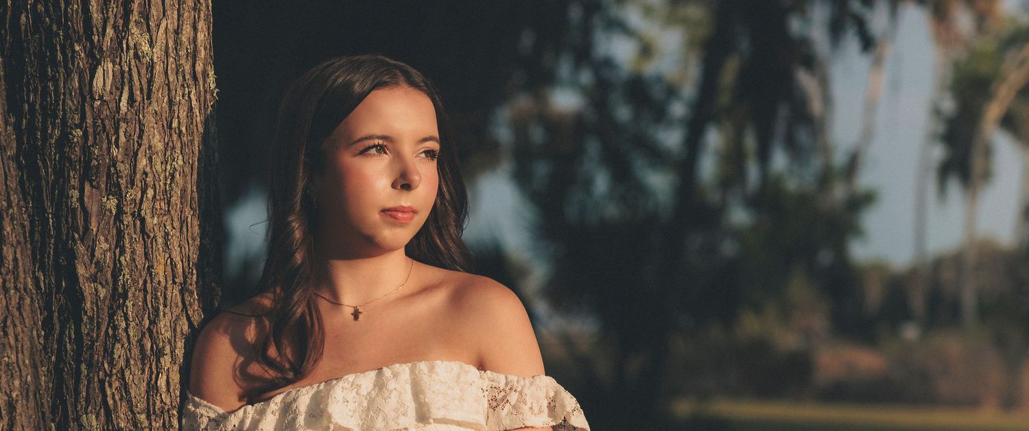 Artistic outdoor portrait session with natural lighting and tree elements in the background.