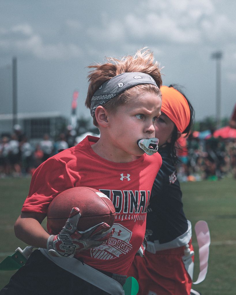 Player in red Under Armour uniform competing in sports match on outdoor field.
