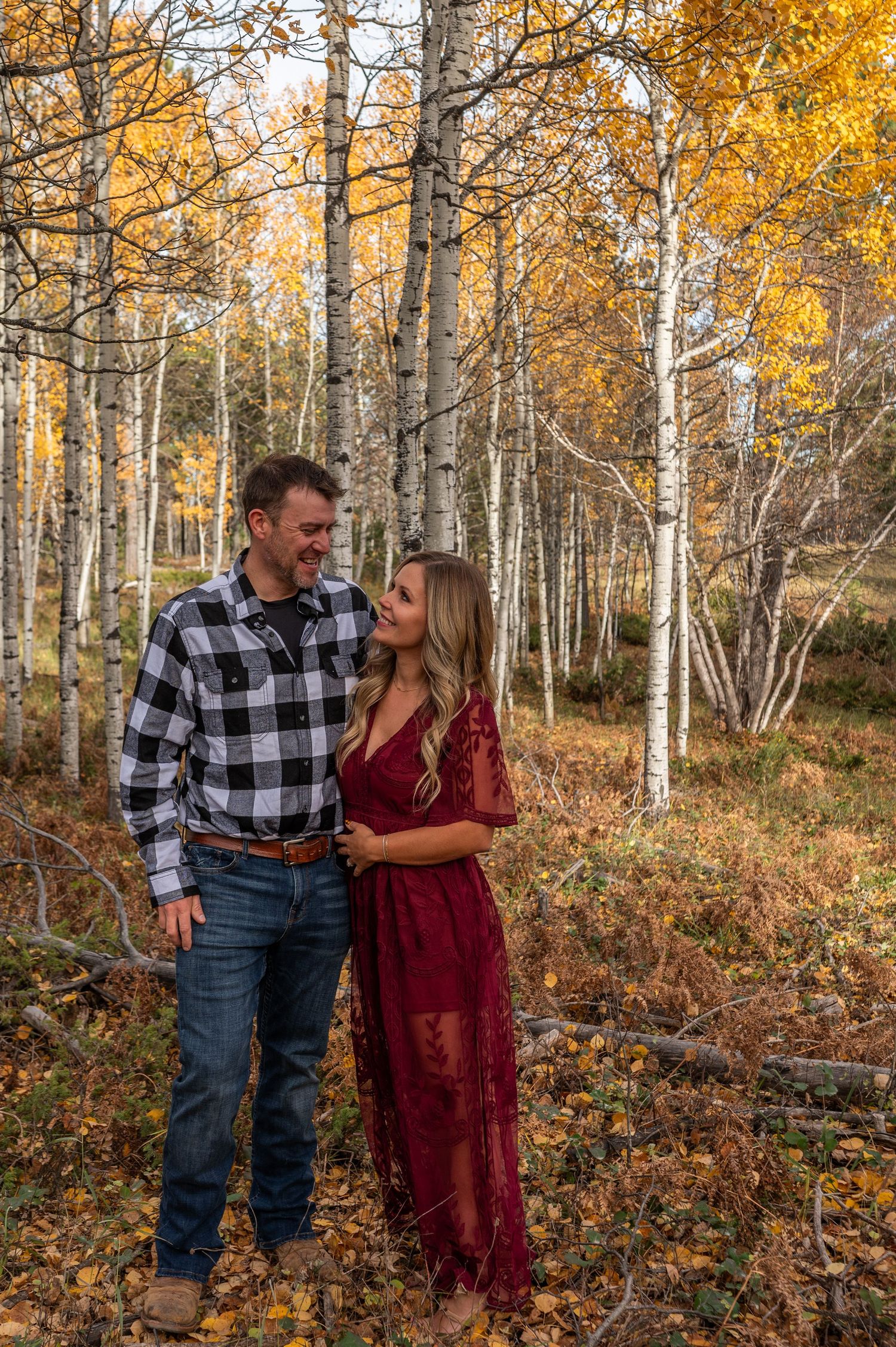 A couple in the black hills of South Dakota are smiling at one another during a fall session