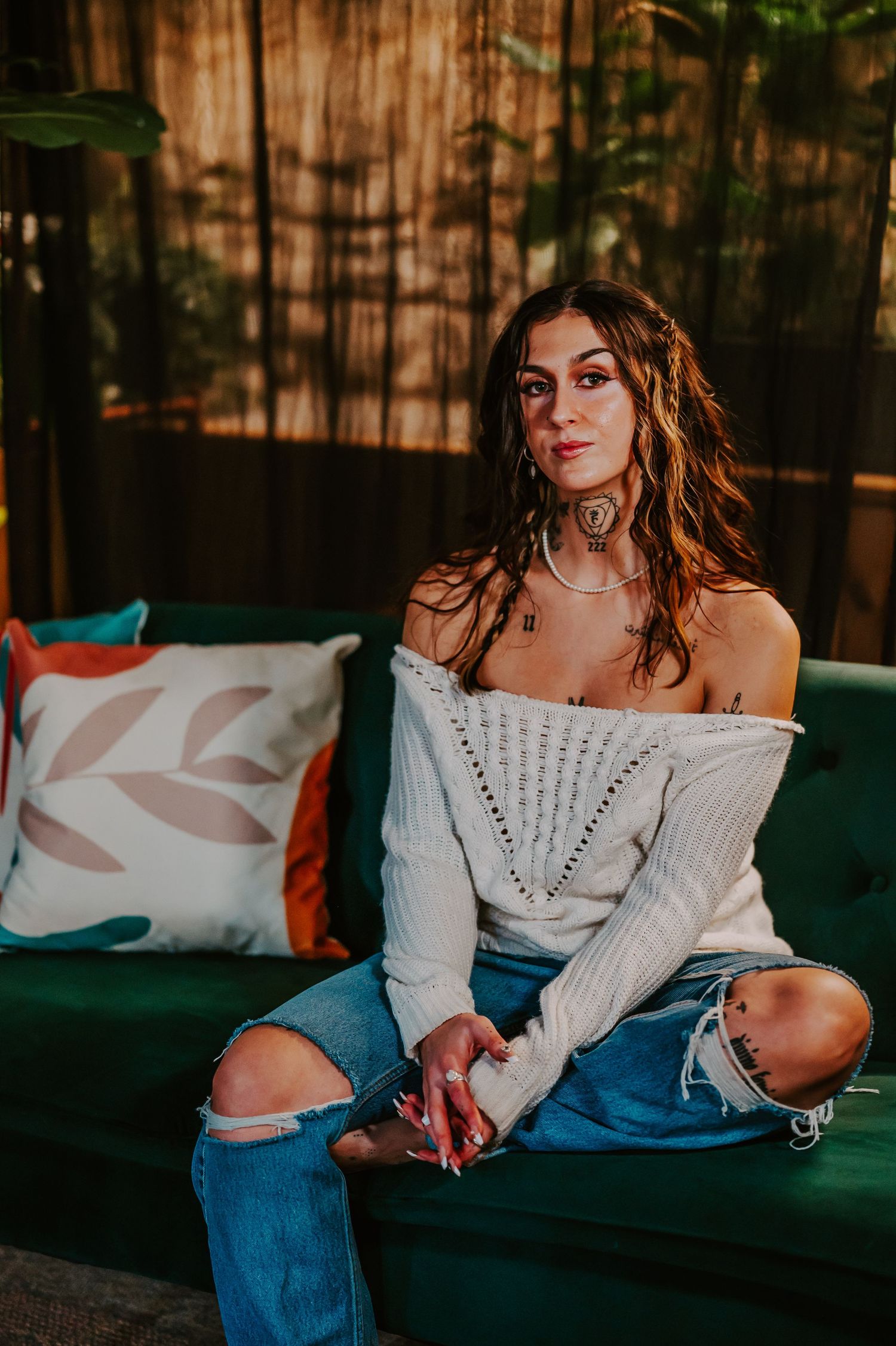 A casual lifestyle portrait series on a dark blue couch featuring an off-shoulder white sweater and blue jeans outfit.