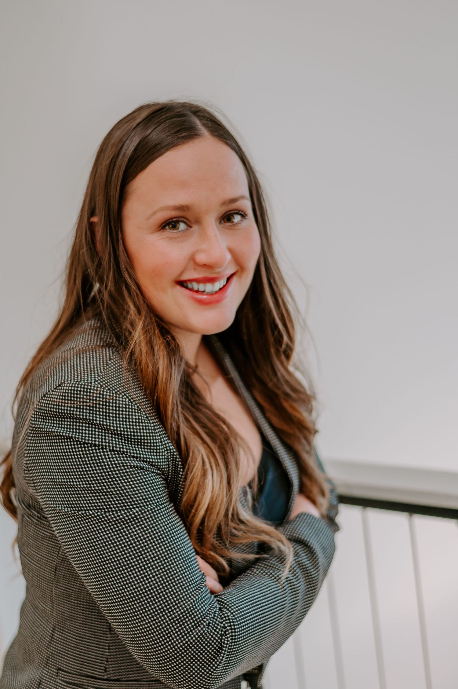 Business portrait in textured green blazer on stairs with neutral background.