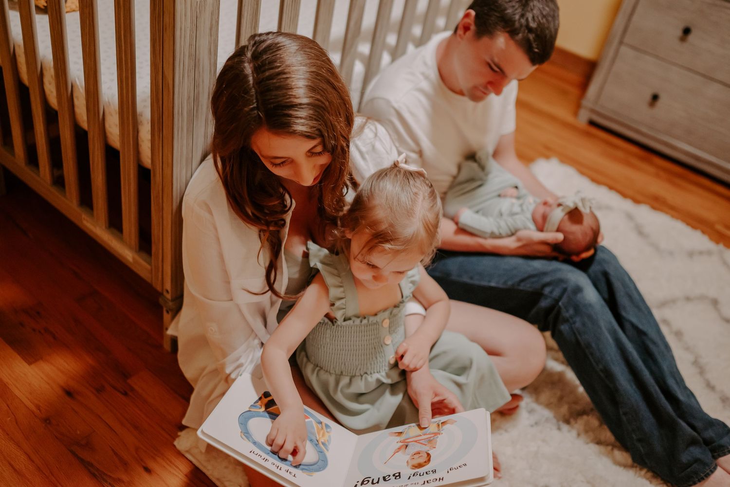 Family reading a book to their children in their nursery