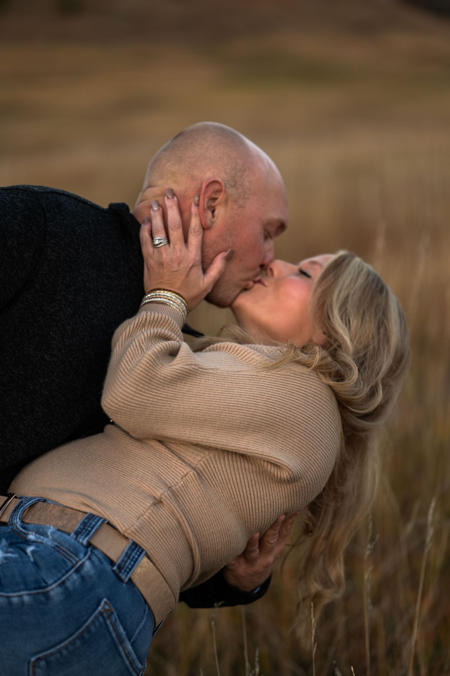 A couple in spearfish South Dakota are kissing in a hay field