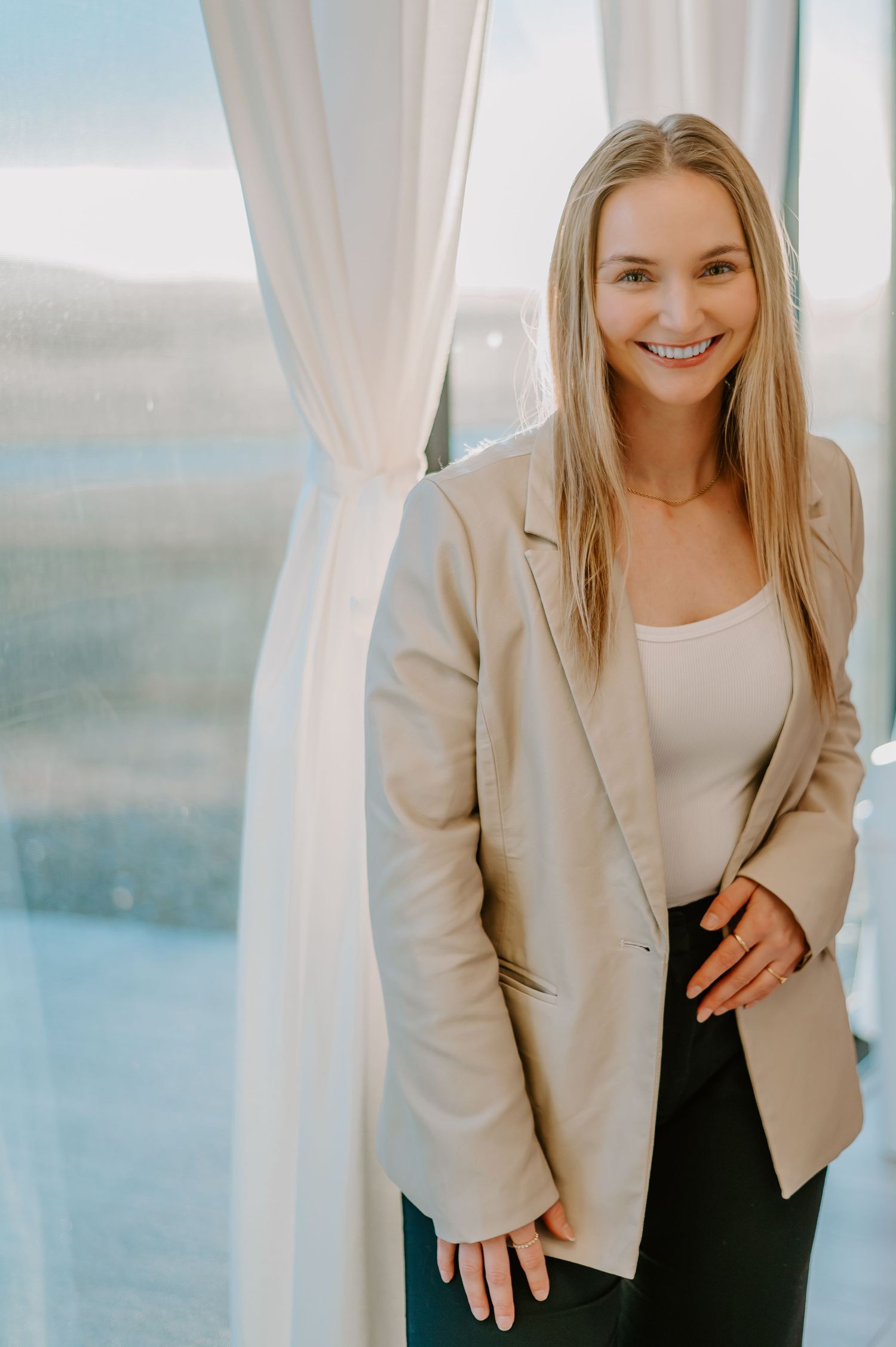 Portrait series against bright window showing person in beige blazer and white top.