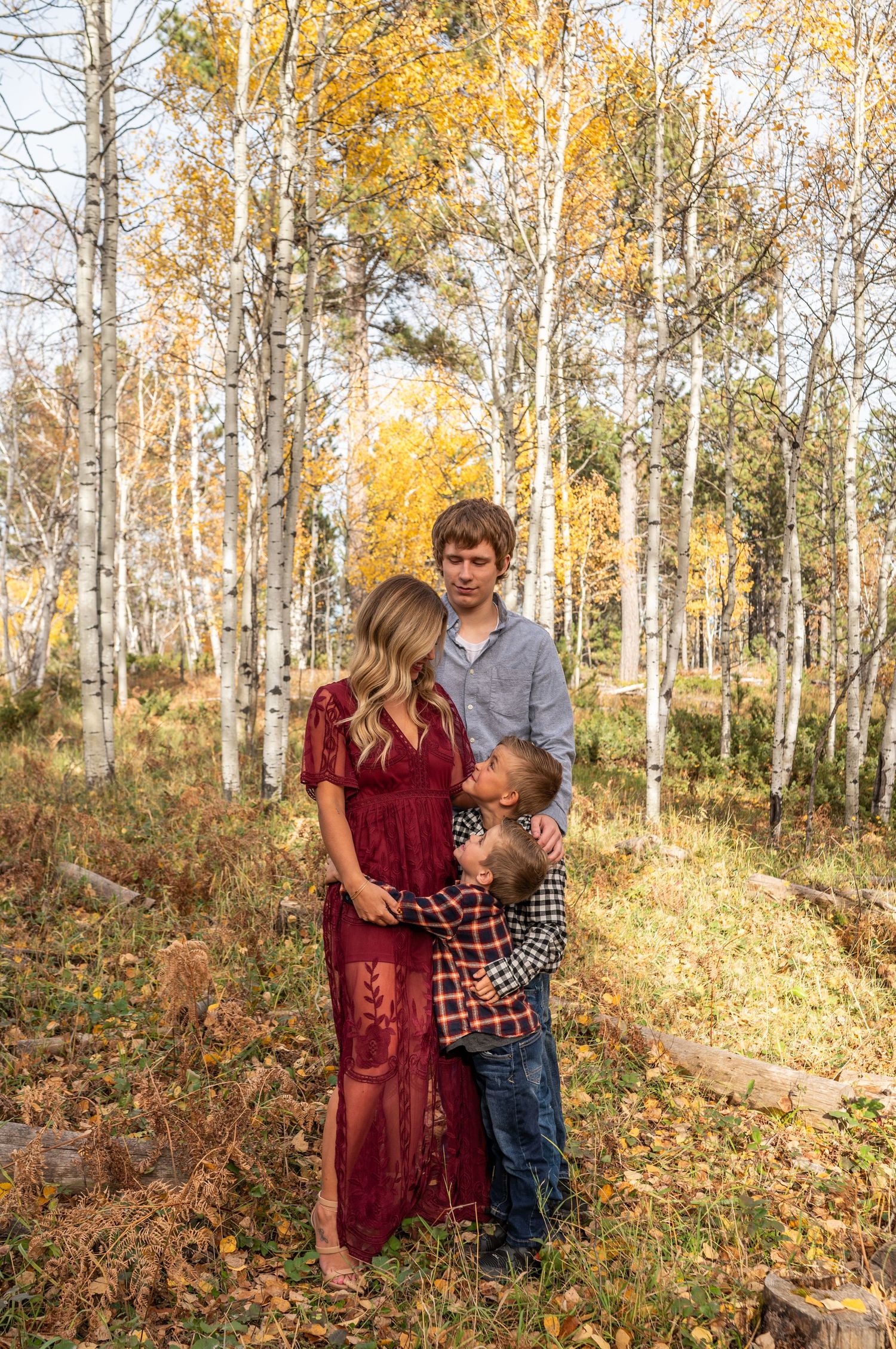 Family portrait session in a golden autumn aspen grove with warm sunlight filtering through the trees.