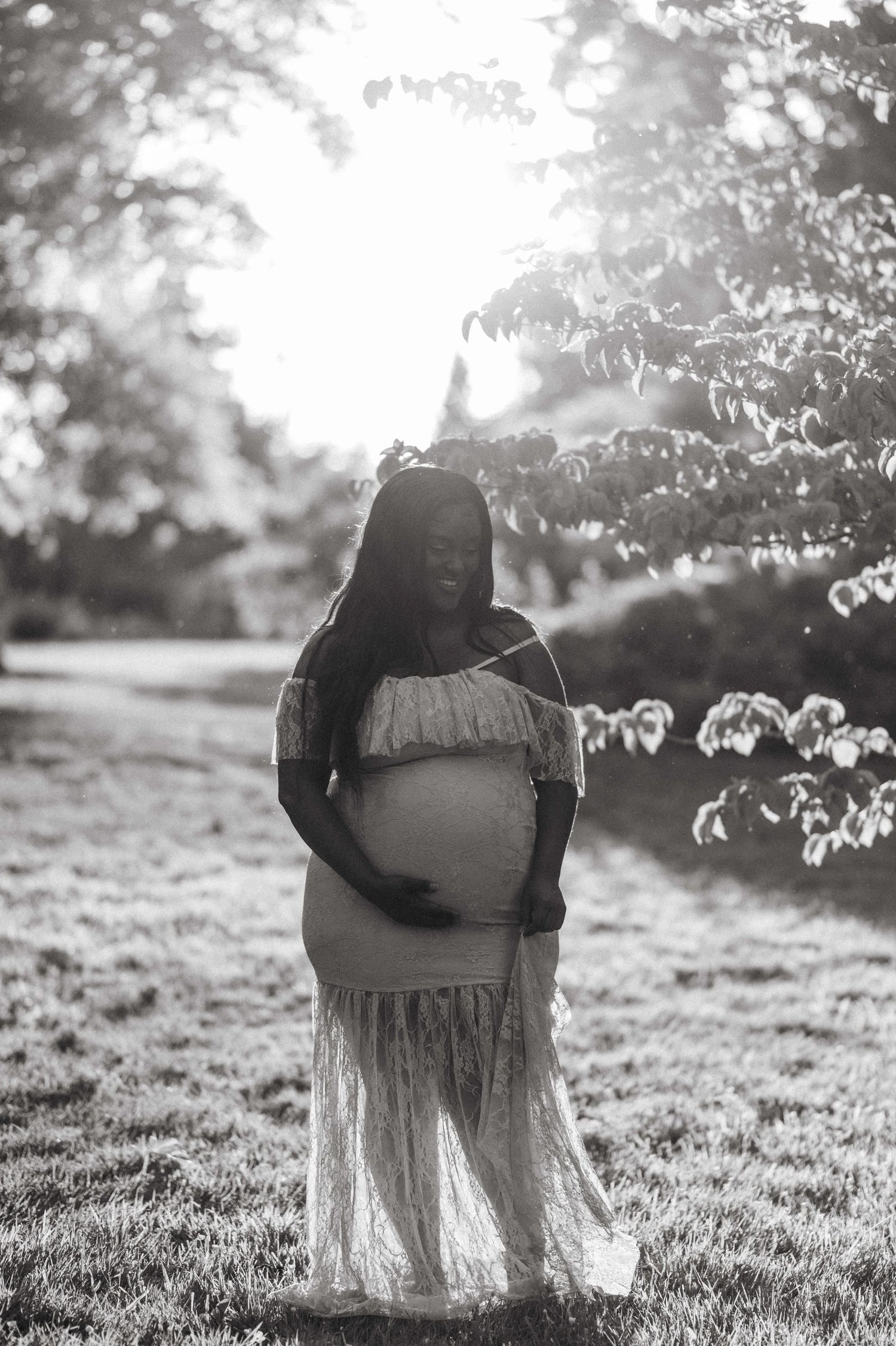 Ethereal outdoor portrait in a grassy field with sunlight filtering through tree branches.