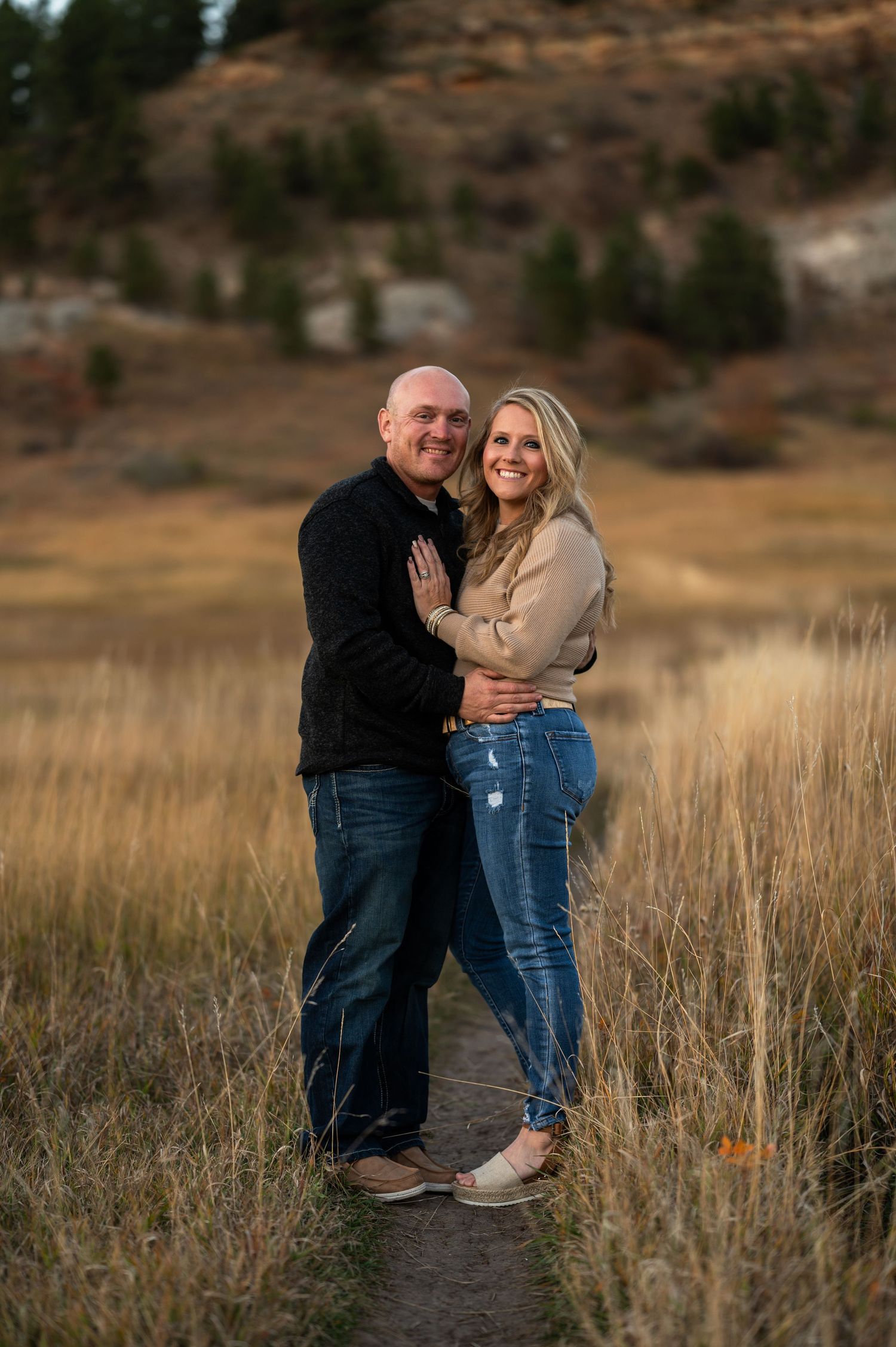 A couple in spearfish South Dakota are holding one another in a hay field
