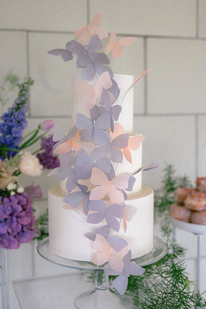 Elegant wedding cake adorned with pink and purple butterfly decorations, perfect for Riga celebrations