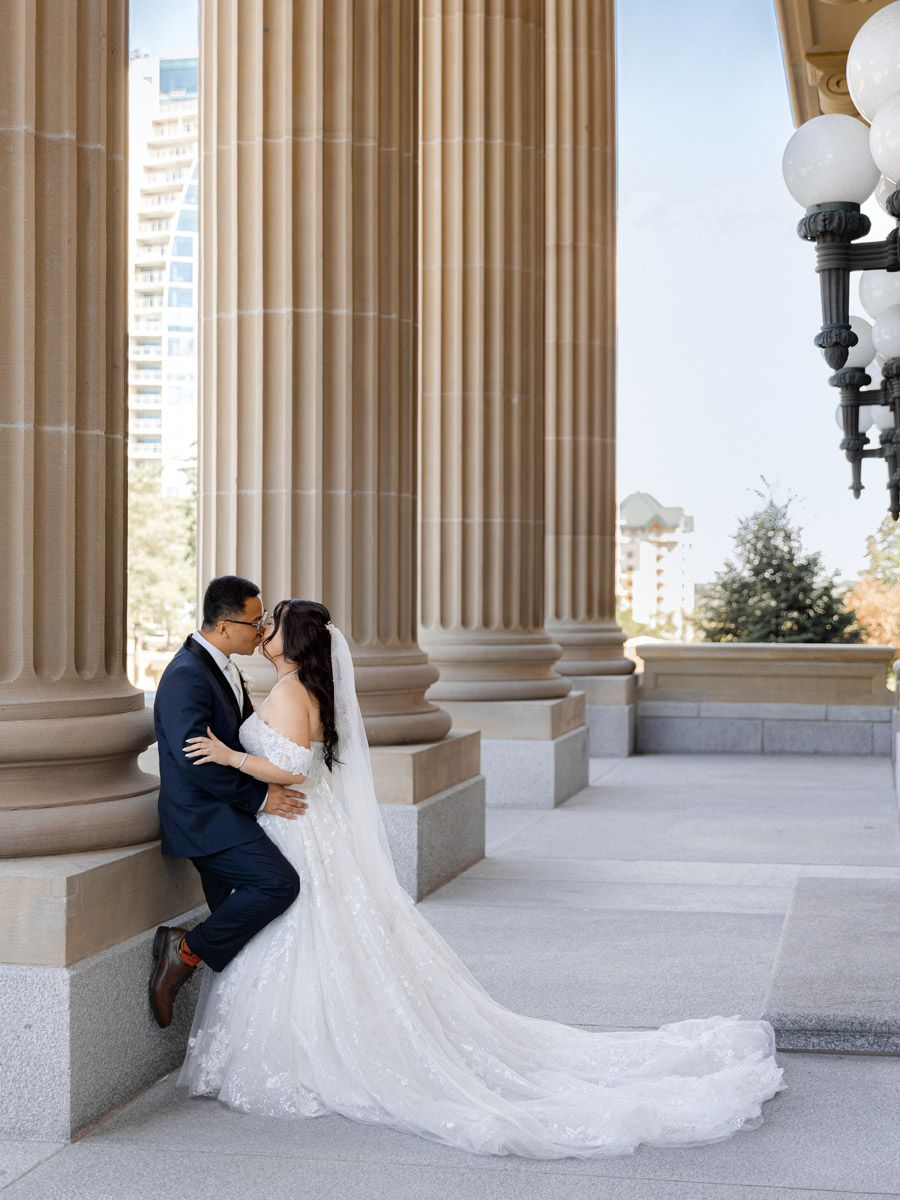 Bride and groom framed by grand columns, elegant Riga wedding portrait