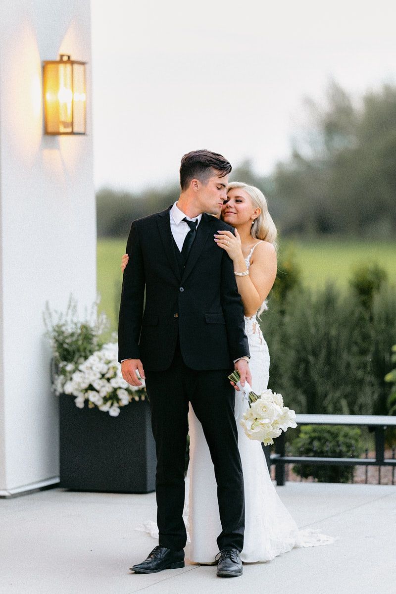 The couple shares a loving glance while standing in front of the grand arched doors in Riga