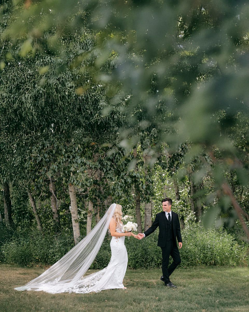 The bride and groom share an intimate embrace on the scenic grounds of Latvian wedding venue