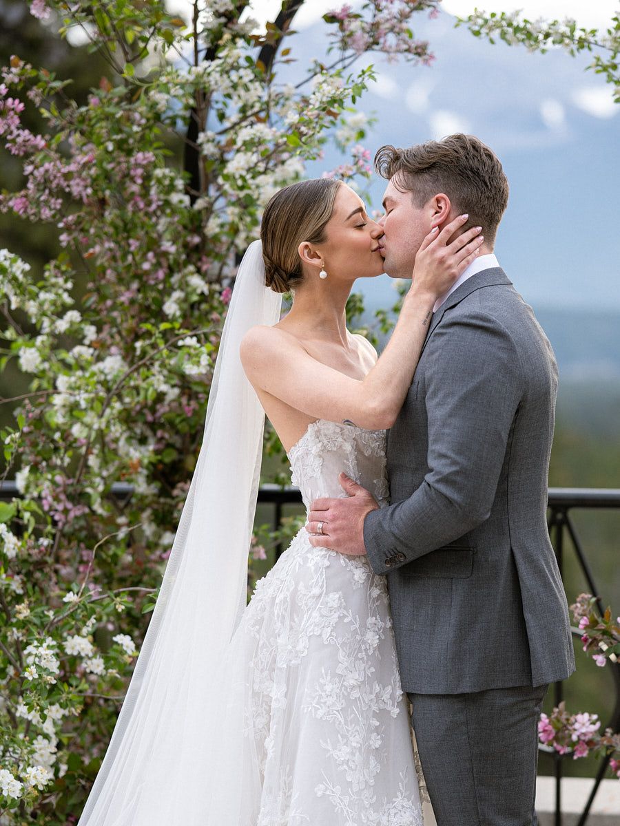 Bride and groom kissing under a floral wedding arch, capturing elegant Riga ceremony moments
