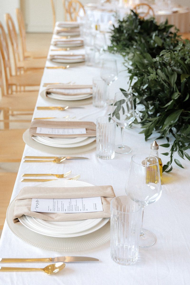 Elegant wedding table setting with plate, utensils, and green floral decor, ideal for Riga receptions