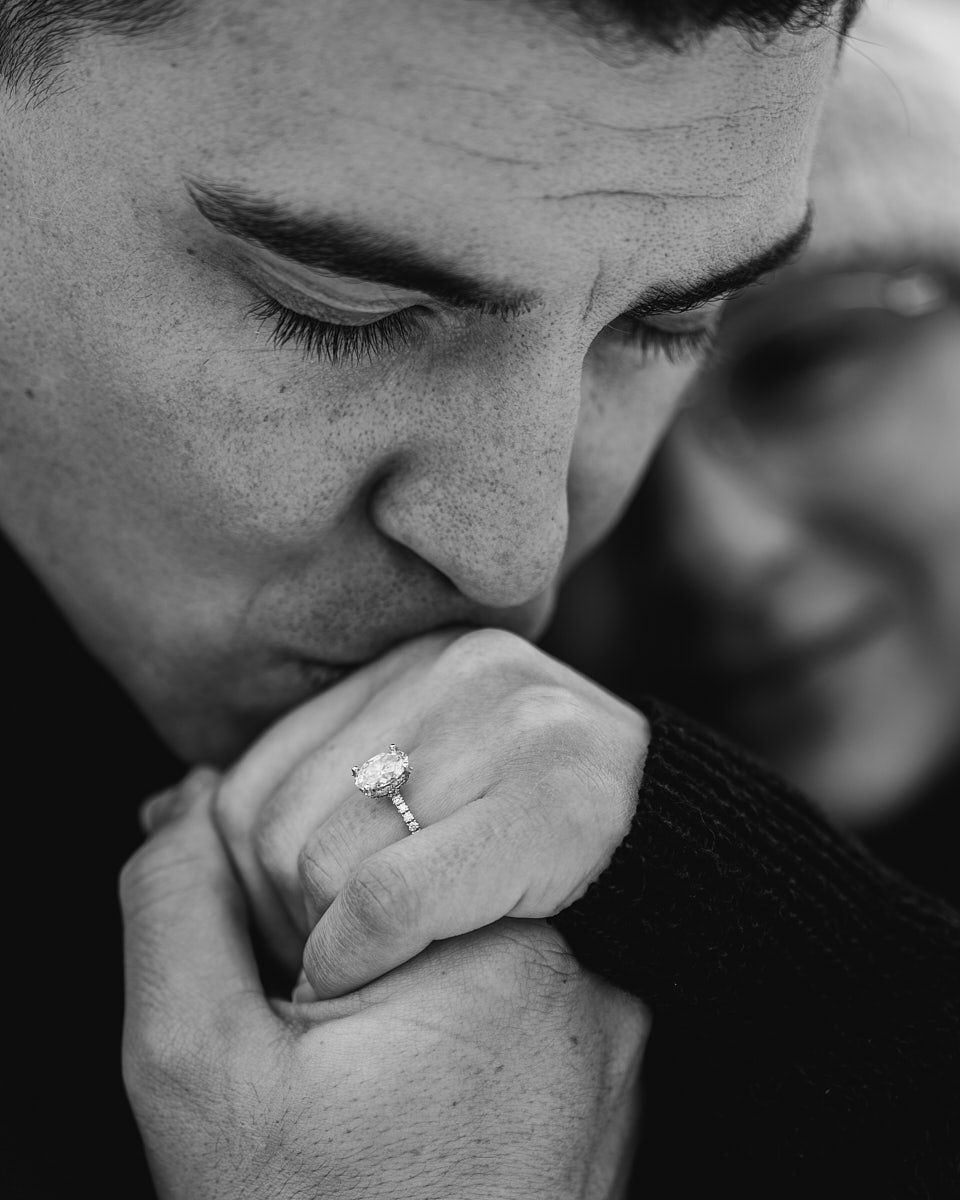 Man kissing fiancée’s hand showing engagement ring, romantic proposal moment in Europe