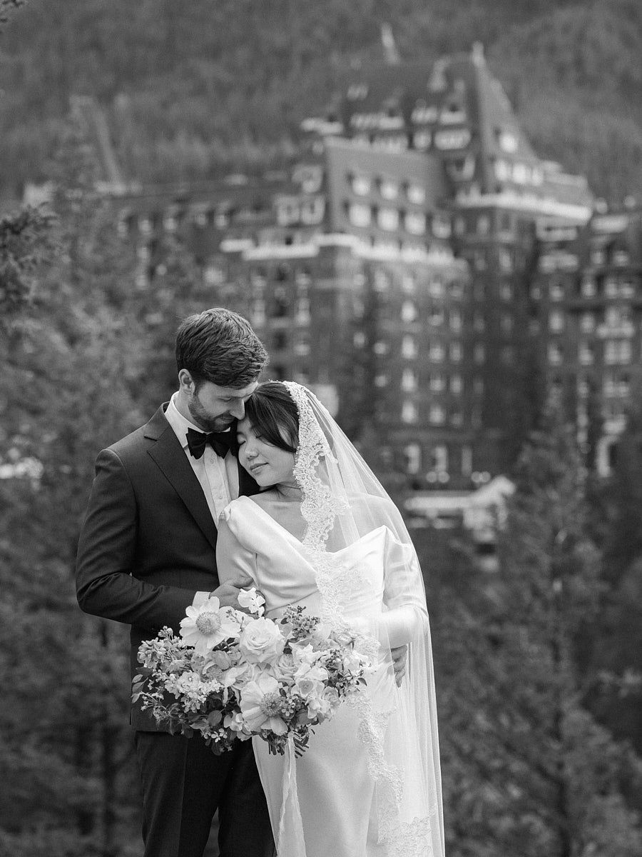 Bride and groom captured in timeless wedding portraits with castle and forest backdrop