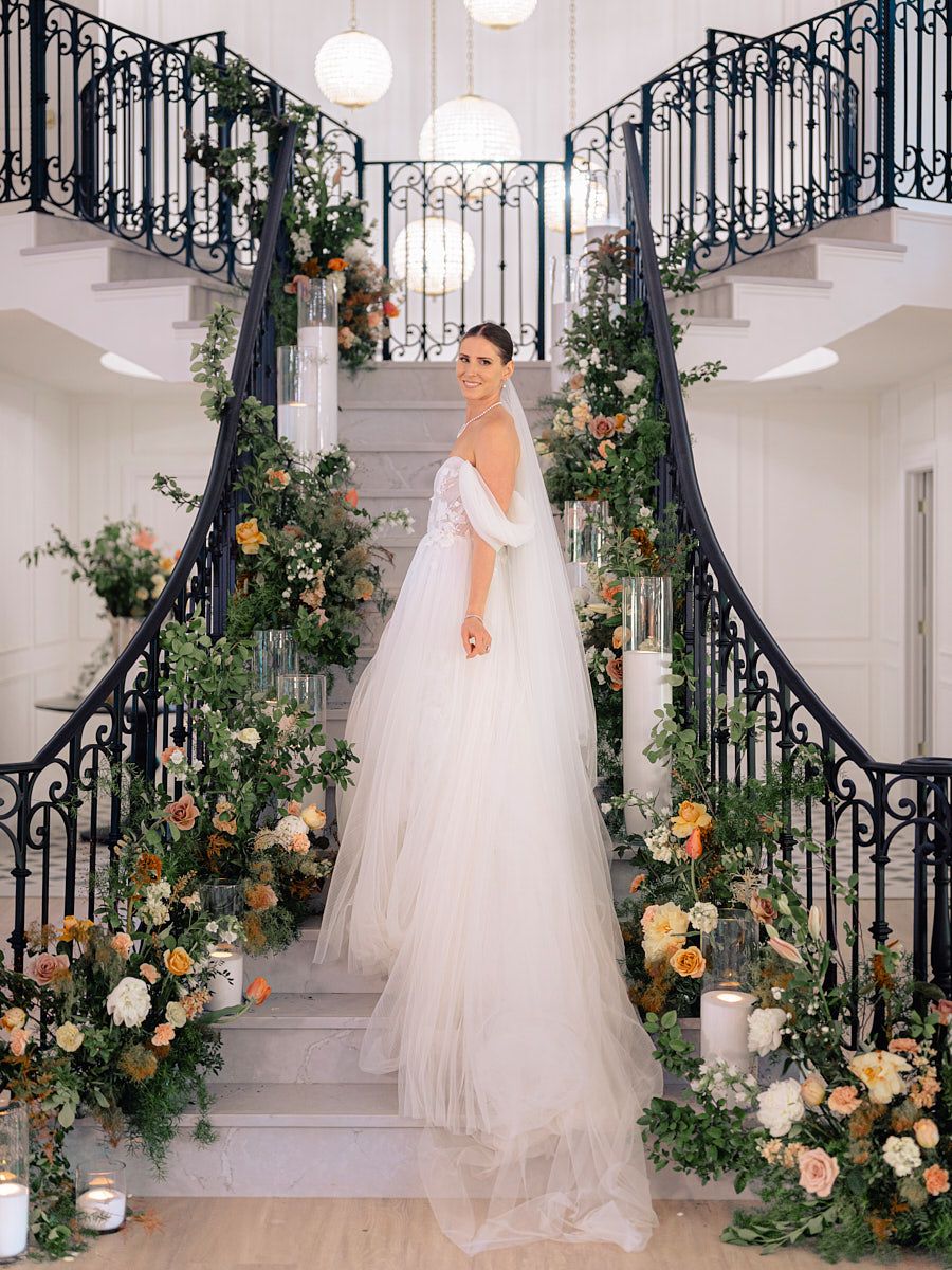 Sophisticated bridal pose on Riga grand stairs, classic wedding portrait with flowing dress