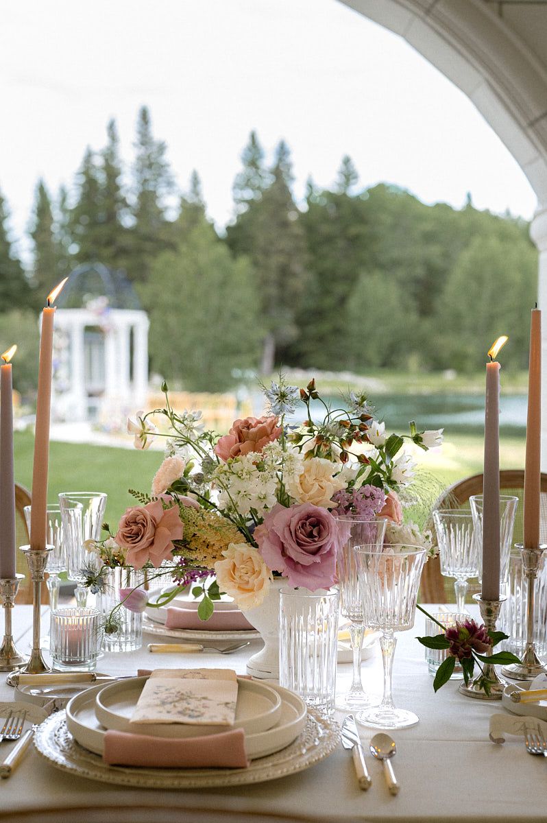 European-inspired pastel wedding tablescape with elegant plates, glasses, and flowers