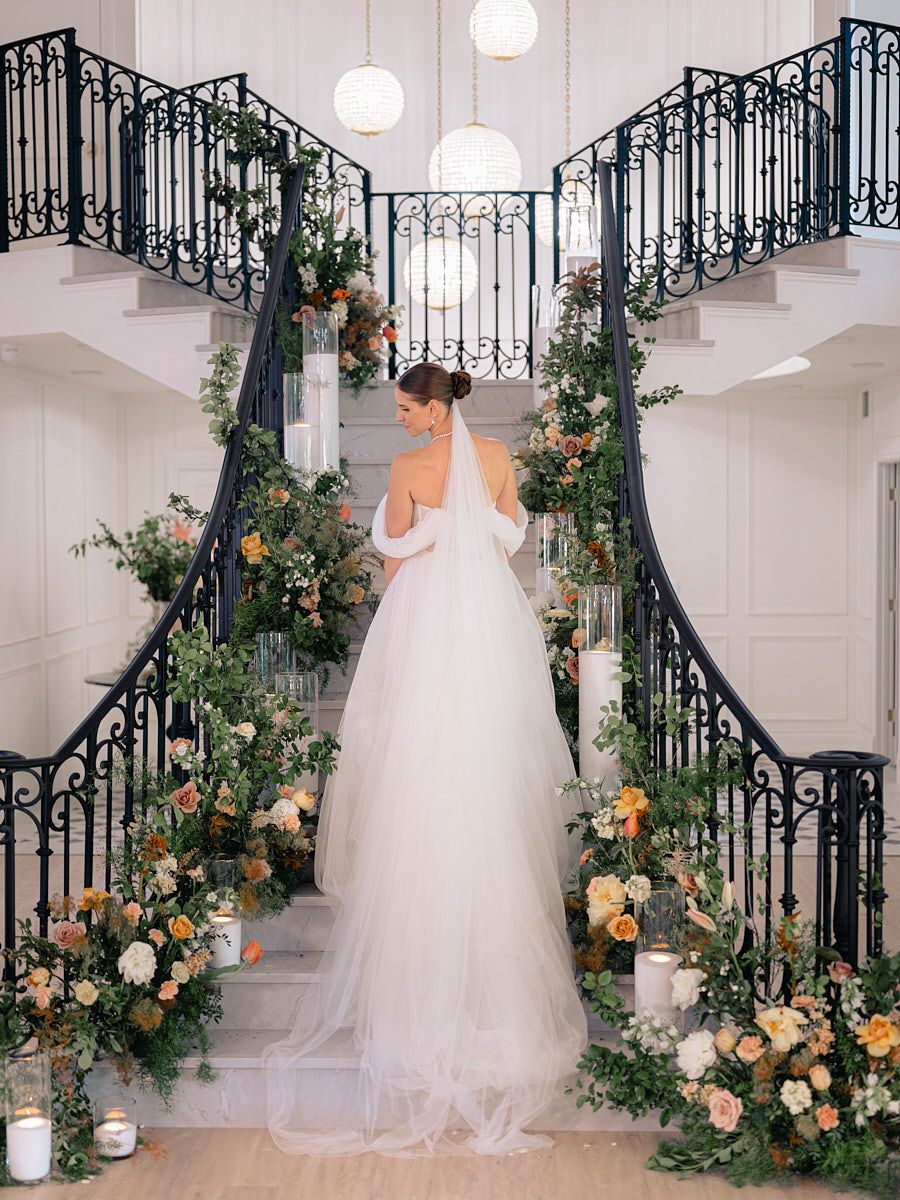 Bride descending grand staircase, romantic Riga wedding moment in soft natural light