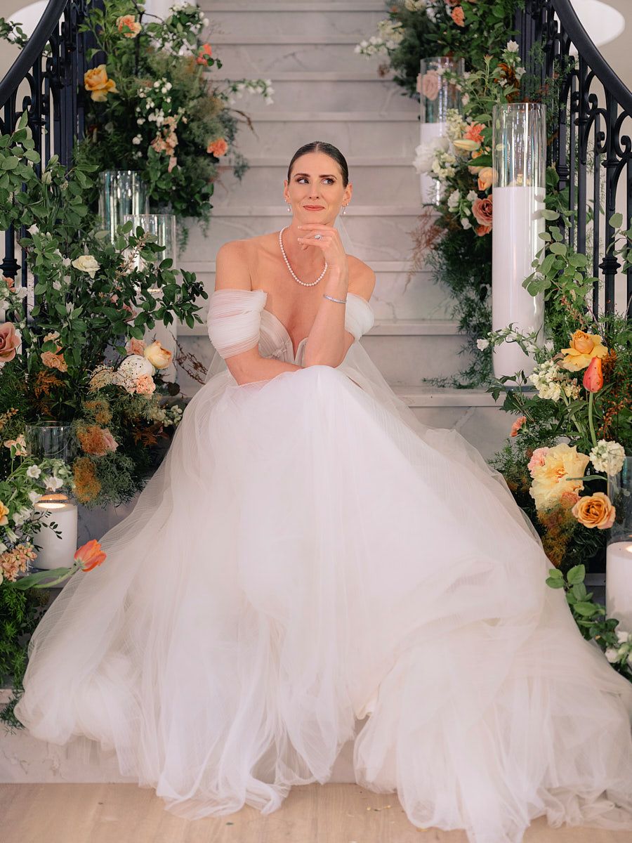 Elegant bride posing on grand stairs, classic Riga wedding portrait in natural light