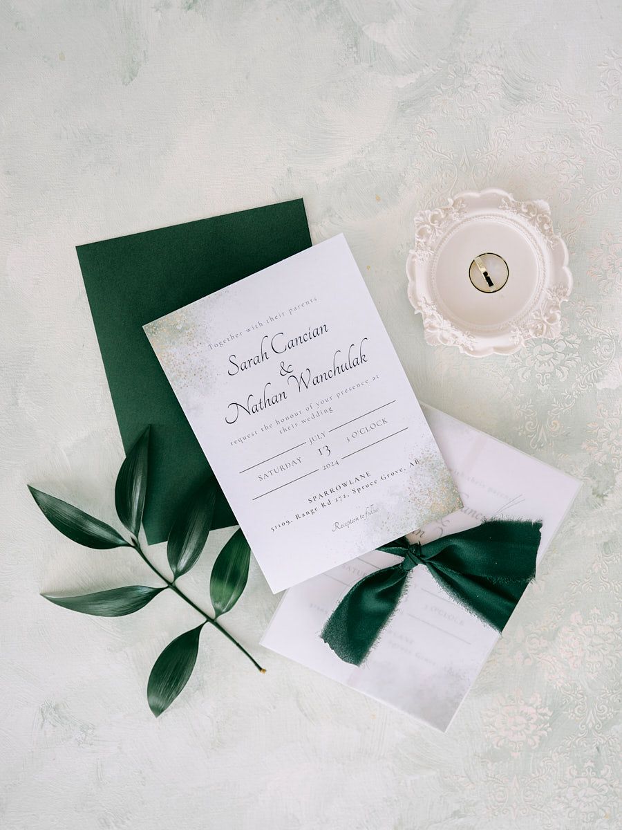 Wedding invitations and rings styled with lush greenery for a romantic flat-lay at a Lavian wedding venue
