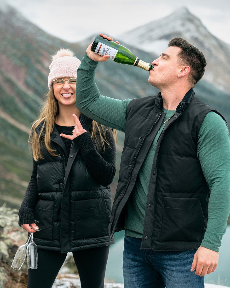 Engaged couple celebrating with champagne in the mountains, romantic Europe engagement shoot